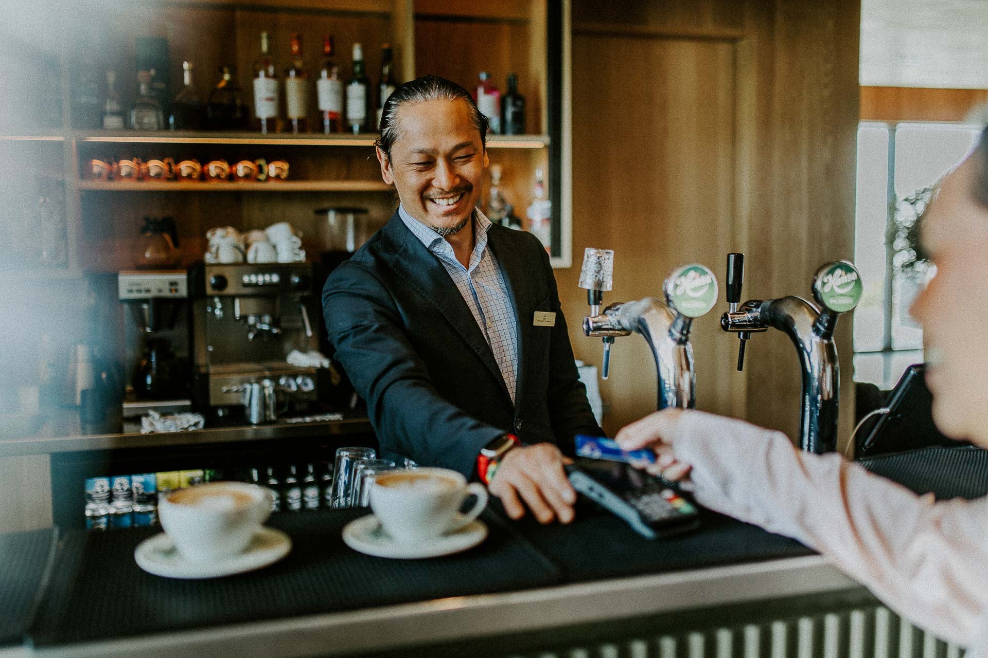 Reklamefotografering til kampanje for Altibox bedrift tatt i naturlig lys utstein kloster hotell ansatt tar i mot betaling i baren