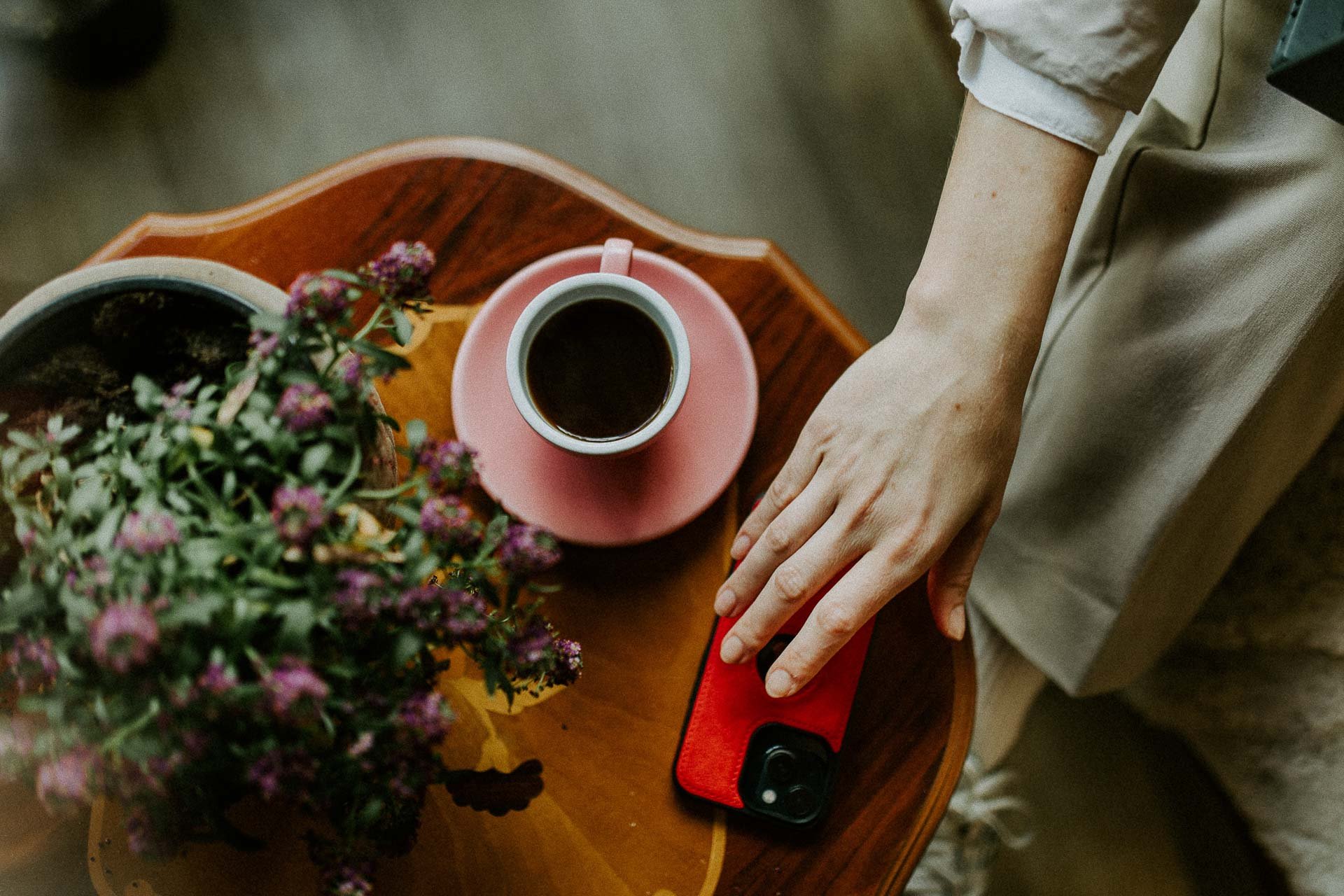 Reklamefotografering til kampanje for Altibox bedrift tatt i naturlig lys detaljebilde av hånd som tar etter mobiltelefon på kafe rosa kaffekopp blomster