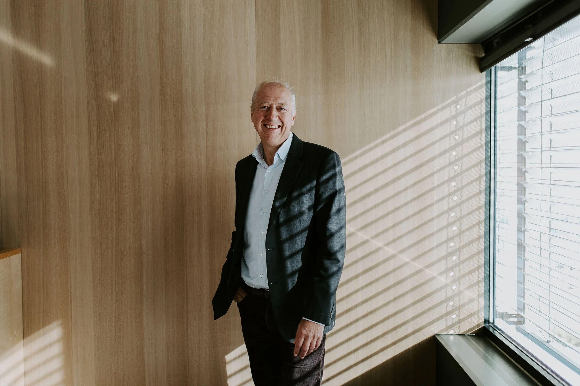 Direktør ser mot kamera kraftige lys striper fra høyre smiler halvfigur reklamefotografering for nofo norsk oljevernberedskap tatt i naturlig lys