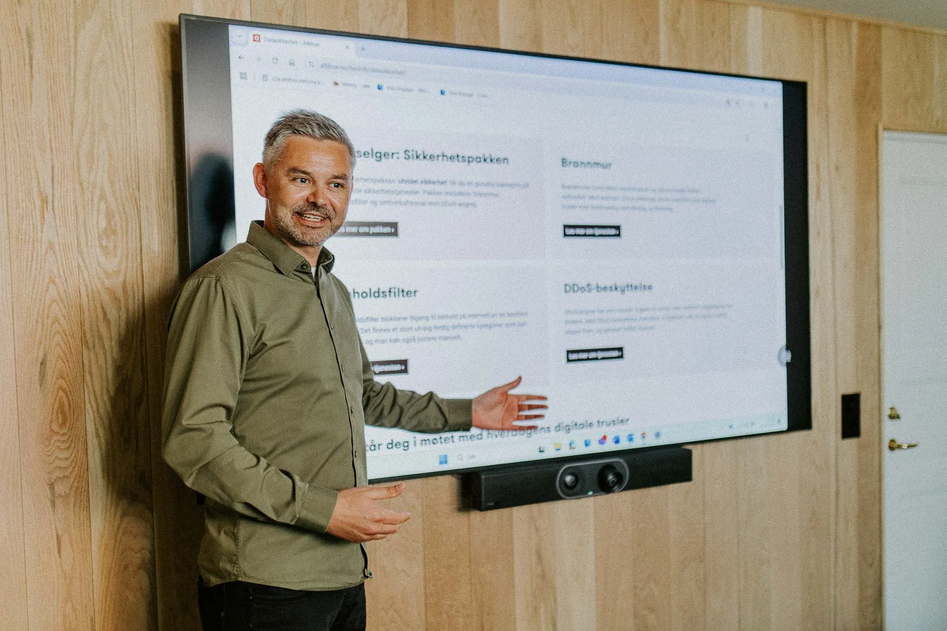 Reklamefotografering til kampanje for Altibox bedrift tatt i naturlig lys utstein kloster hotell person som holder foredrag peker mot skjerm og ser mot publikum med et smil