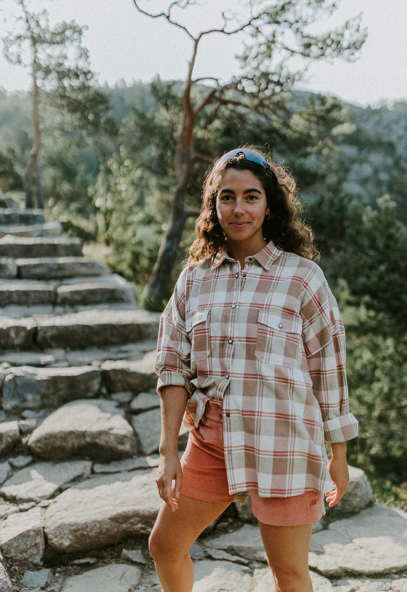 kvinne som ser i kameraet rutete skjorte lav sol skog og trapper bak Reklamefotografering av modeller til kampanje for Skogstad bilder tatt i preikestolenområdet bilder av turklær