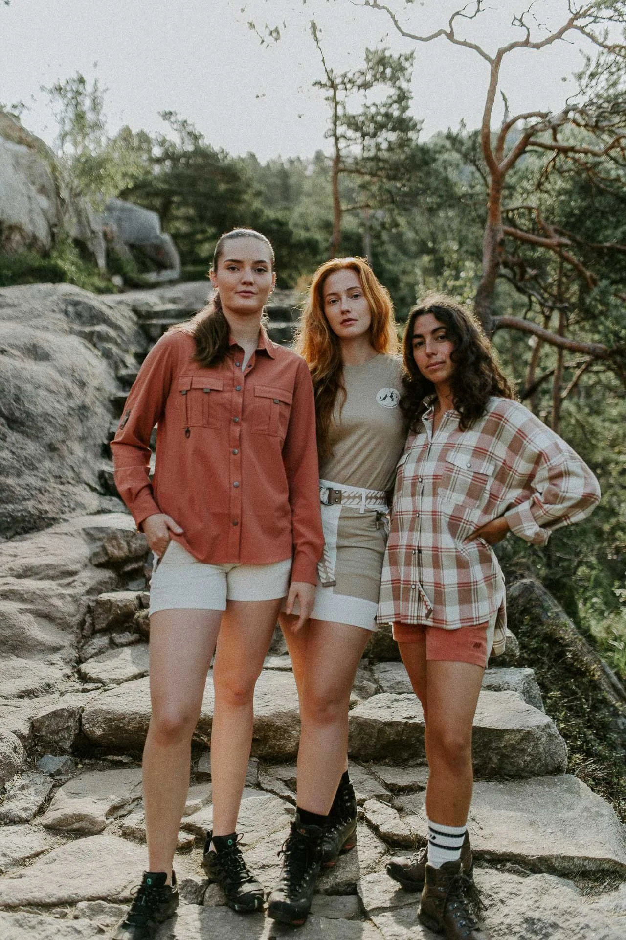 tre kvinner som ser i kameraet og står inntil hverandre, helfigur lav sol og skog og trapper i bakgrunnen  Reklamefotografering til kampanje for Skogstad bilder tatt i preikestolenområdet bilder av turklær