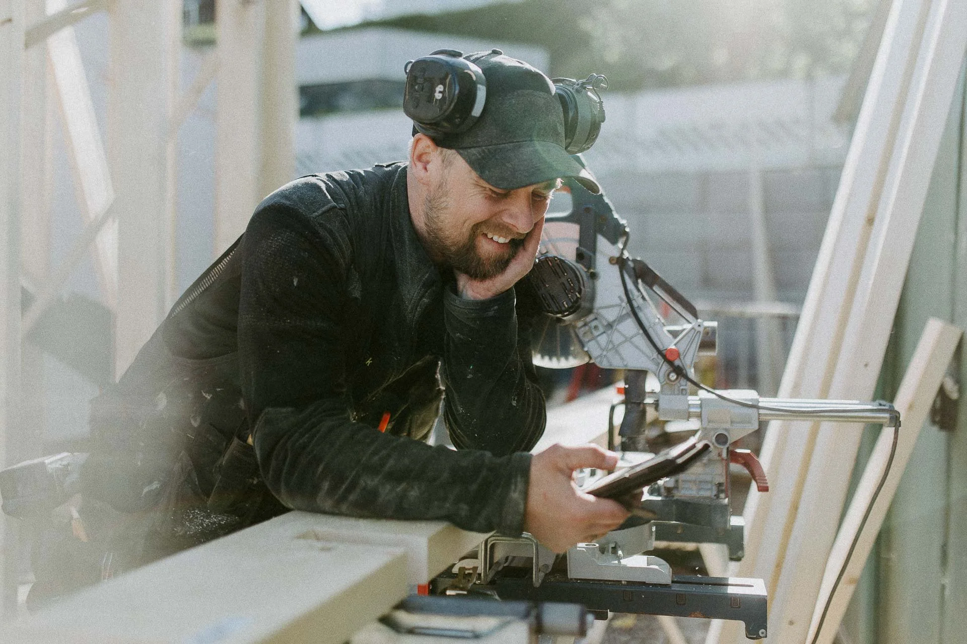 Reklamefotografering til kampanje for Altibox bedrift tatt i naturlig lys bilde av tømrer som er i arbeidssituasjon pusser opp hus på dette bildet ser han på mobiltelefonen