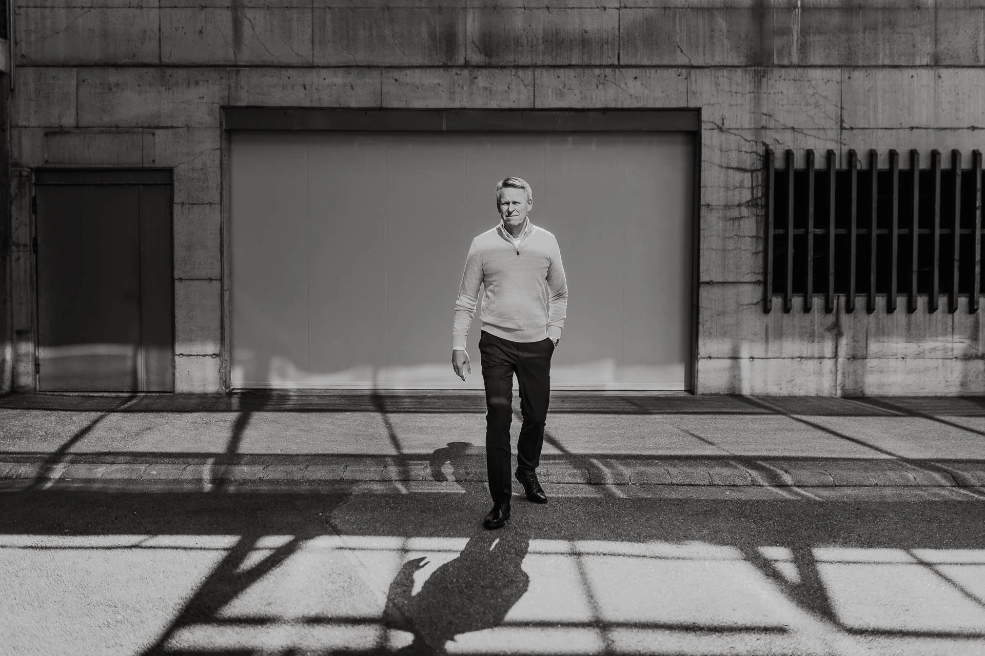Helfigur portrett av direktør i Sorthvitt som går mot kamera men ser til siden kraftige skygger fotografering for zaptec til kampanjebruk og presse naturlig lys verksted westcontrol
