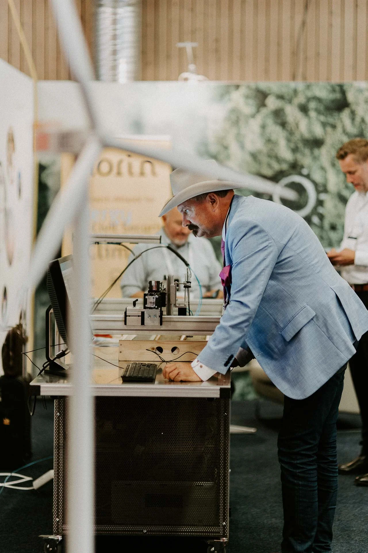 Mannen med cowboyhatt står og ser på skjerm vindmølle i forgrunn tatt ved stand dokumentarfotografering for ONS, Offshore Northern Seas i Stavanger, stavanger forum