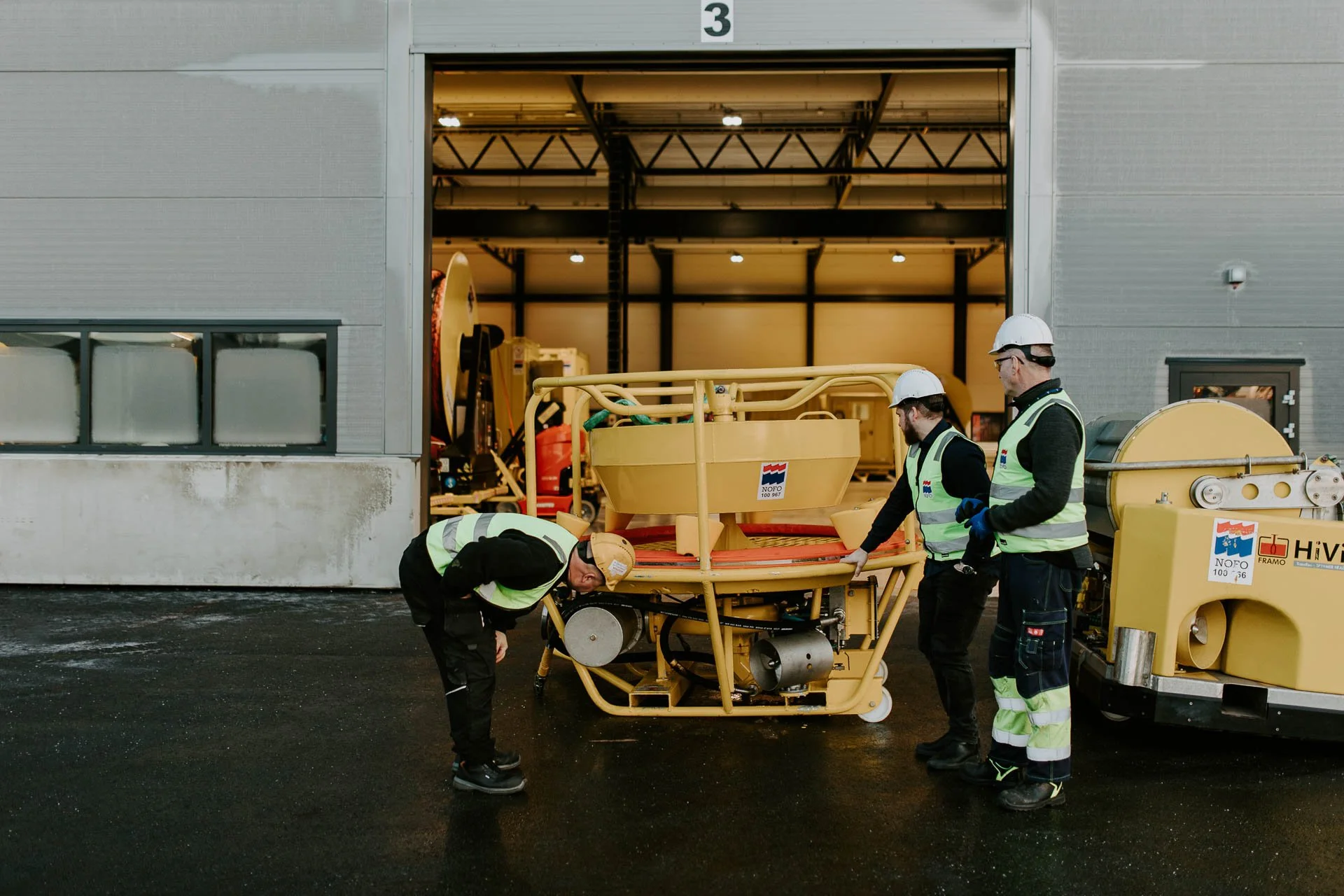 Verksted tre personer i arbeid tatt utenfor verkstedet reklamefotografering for nofo norsk oljevernberedskap tatt i naturlig lys
