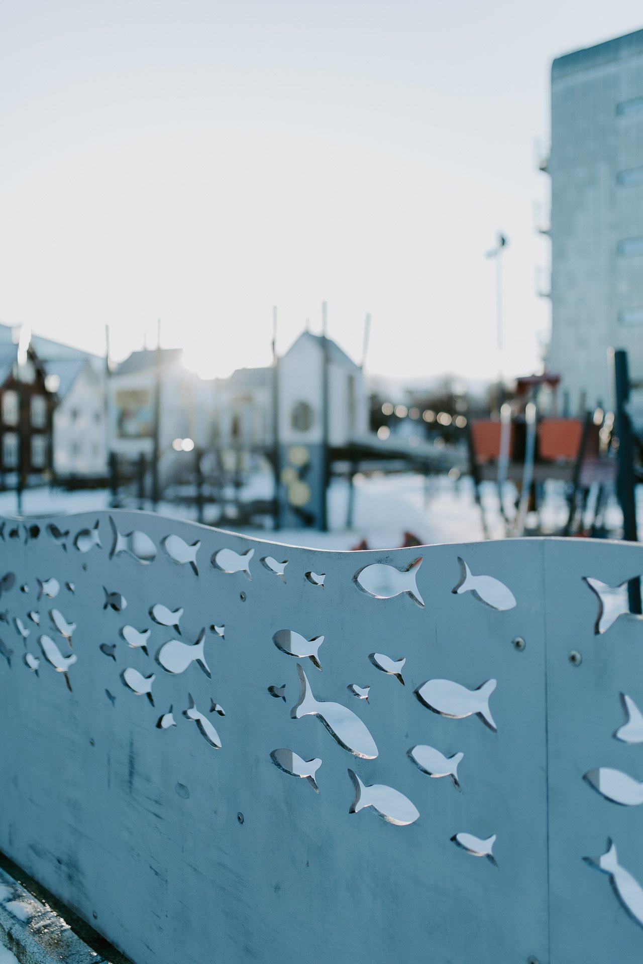Detaljbilde fra lekeplass fisker inn skjært i treplater naturlig lys, reklamefotografering for stavanger kommune, områdesatsingen på Storhaug tatt på vinteren i snø og lav sol