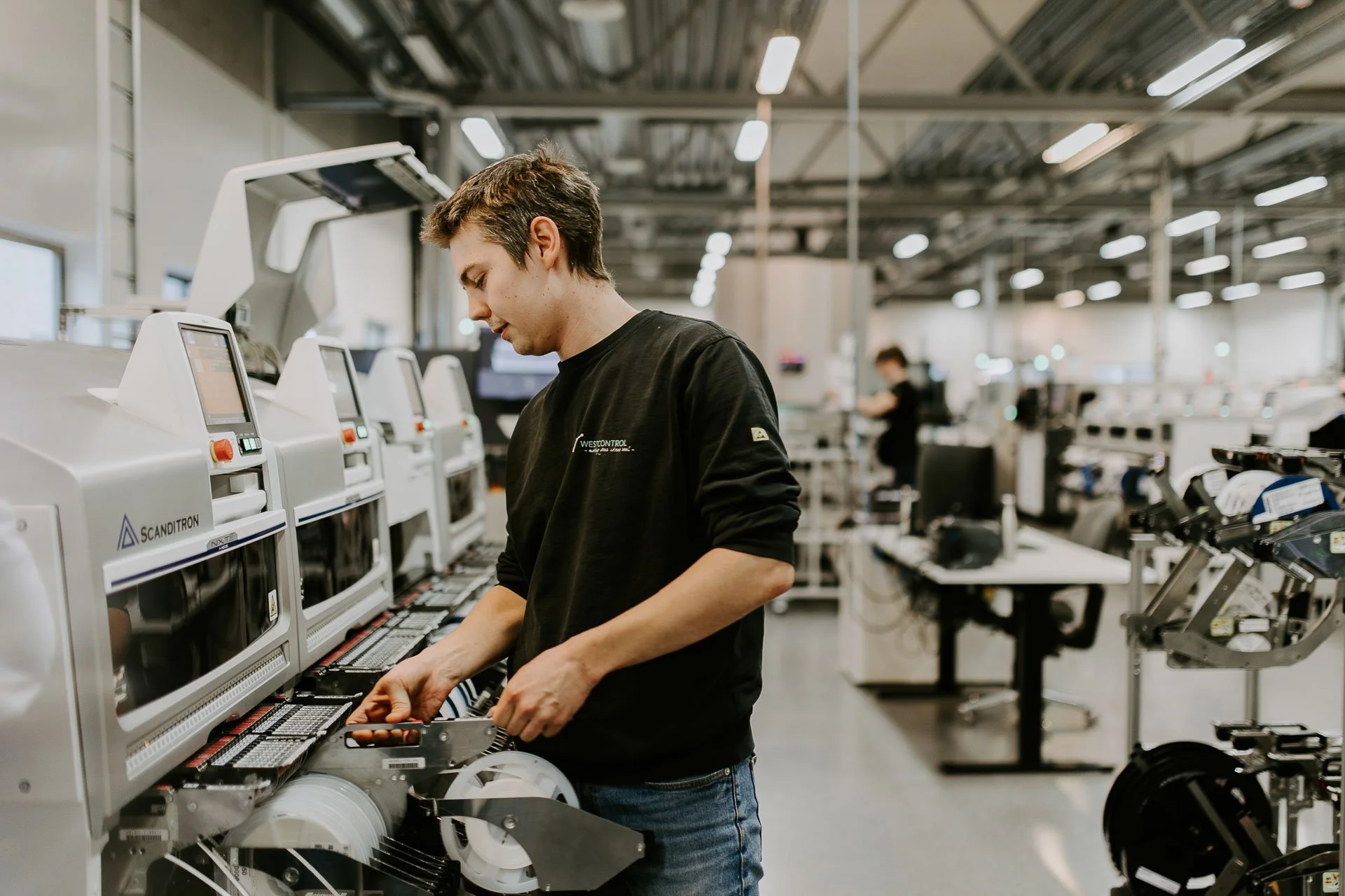 Mann i arbeid med verksted i bakgrunn han jobber med en maskin fotografering for zaptec til kampanjebruk og presse naturlig lys verksted westcontrol