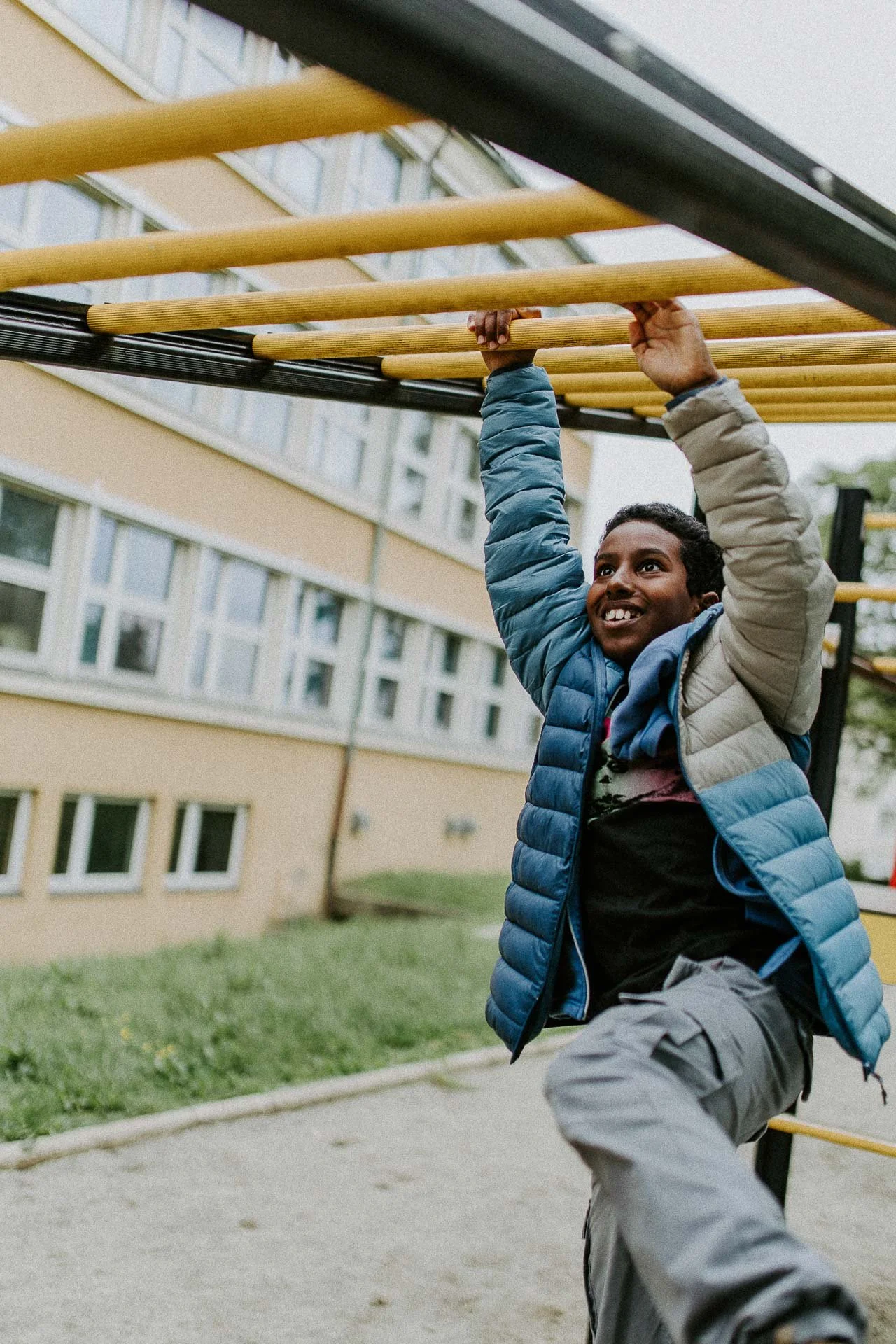 Gutt som klatrer i lekestativ ved Kvalaberg skole han smiler naturlig lys, reklamefotografering for stavanger kommune, områdesatsingen i hillevåg