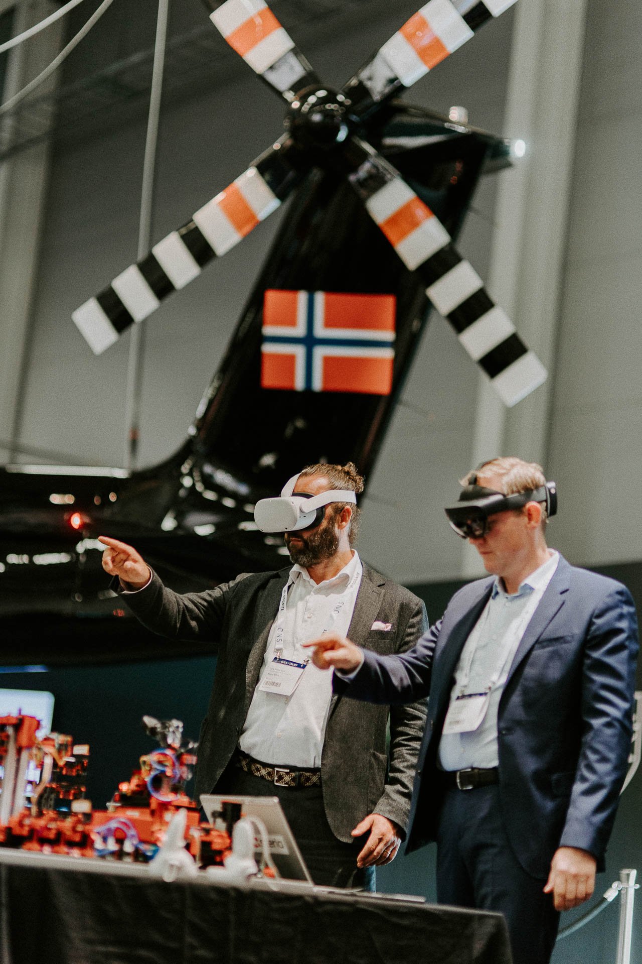 To personer som står med VR briller på og peker et litt humoristisk bilde så ser vi propellen til et helikopter Bakgrunn samt et norsk flagg dokumentarfotografering for ONS, Offshore Northern Seas i Stavanger, stavanger forum