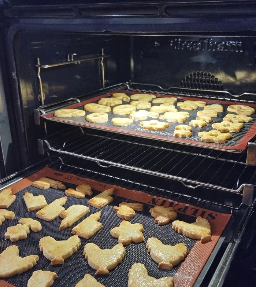 Biscuits en train de cuire dans un four, posés sur des tapis de cuisson.
