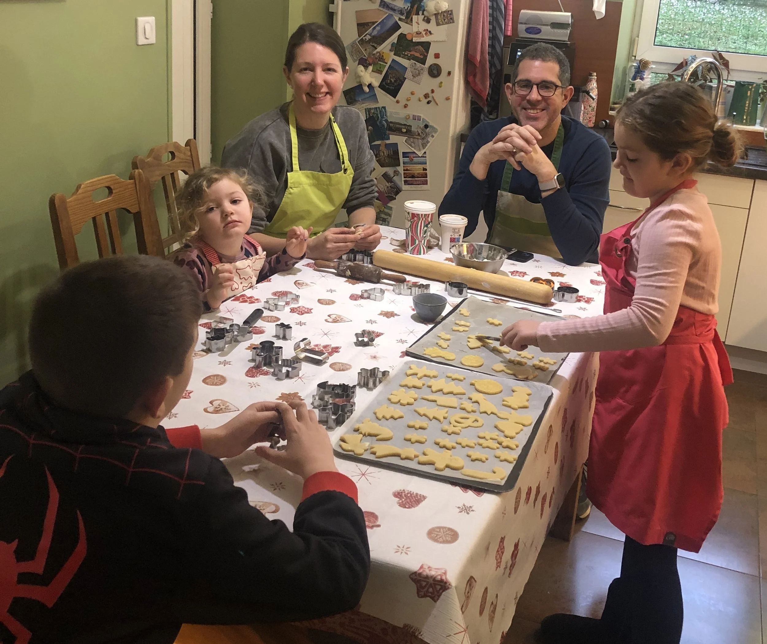 Deux adultes et trois enfants autour d'une table qui confectionne des biscuits de Noël alsacien communément appelé bredele