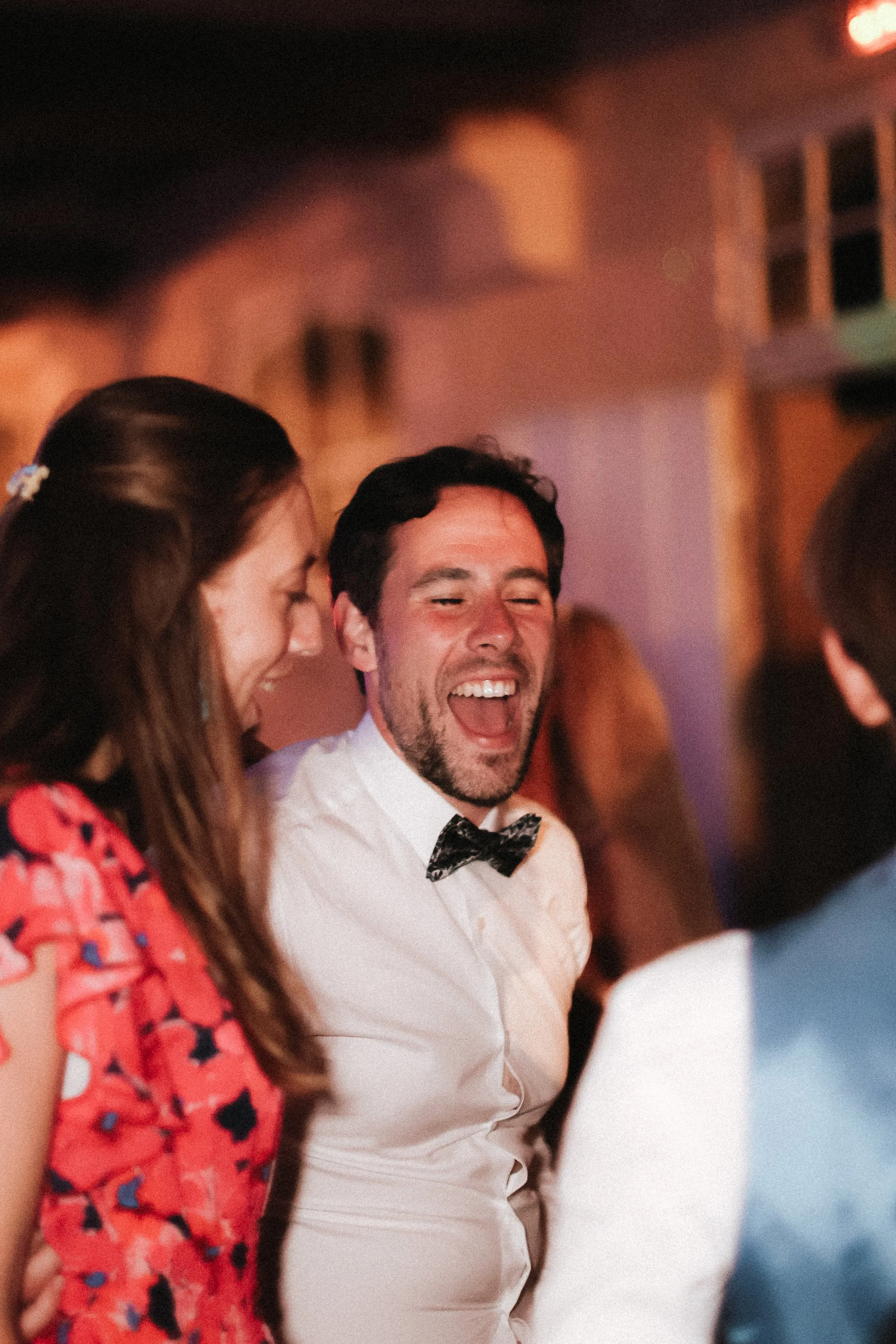 Un groupe de personnes souriantes et riant lors d'une célébration ou d'une fête, dans un environnement intérieur avec une ambiance chaleureuse.