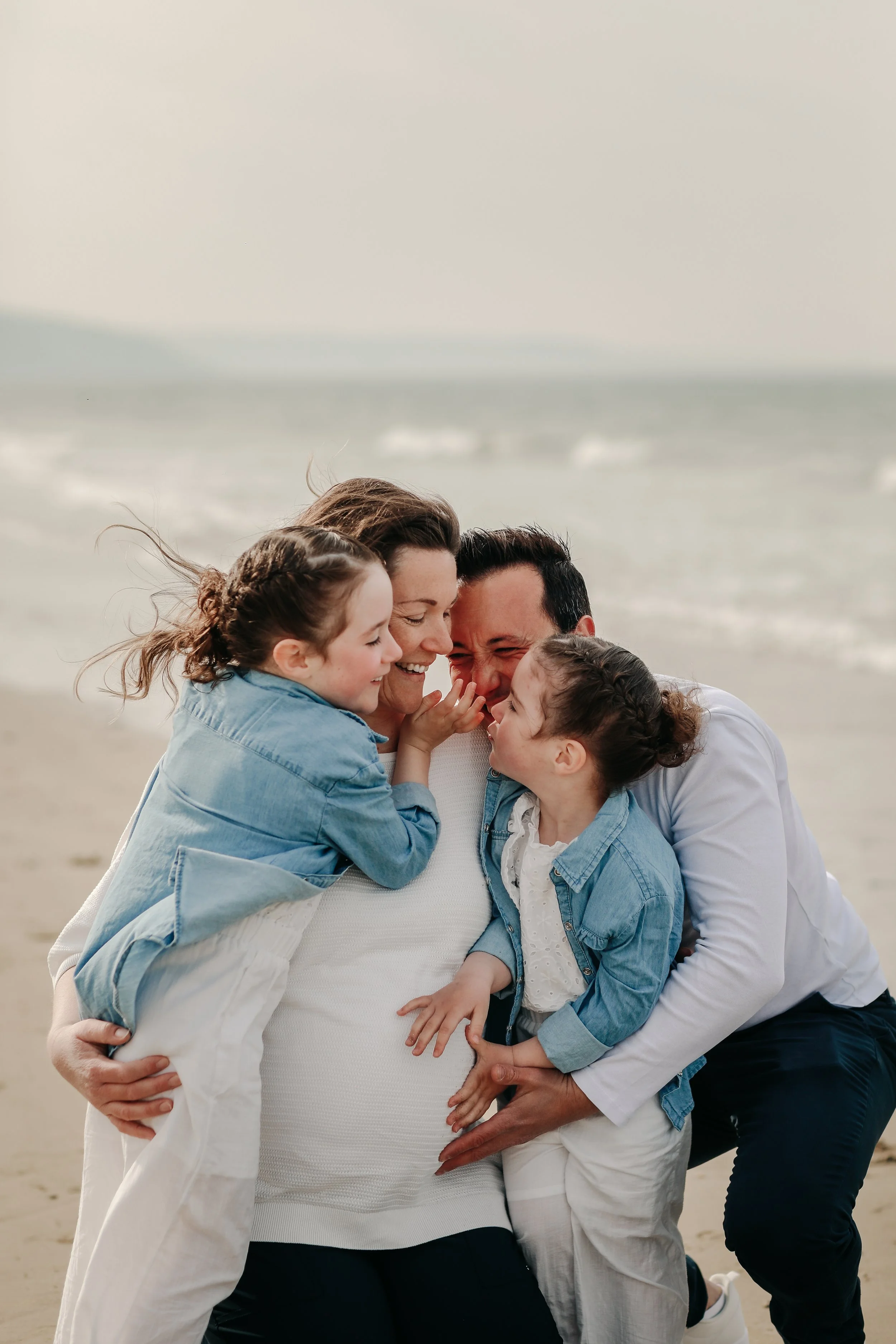 Une famille en groupe joyeux sur la plage, s'étreignant et souriant ensemble.