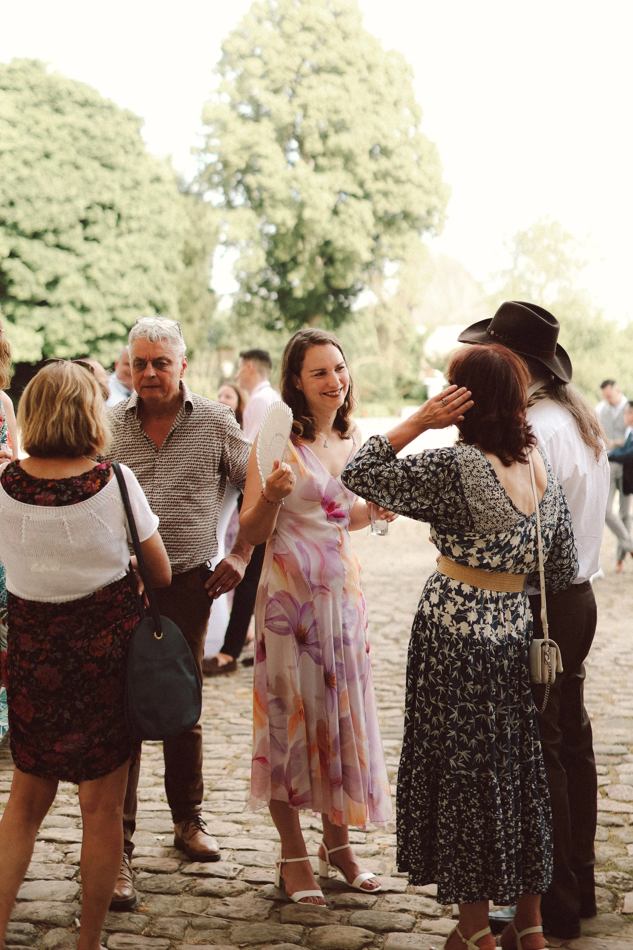 Groupe de personnes discutant lors d'un événement en plein air, sous un grand arbre