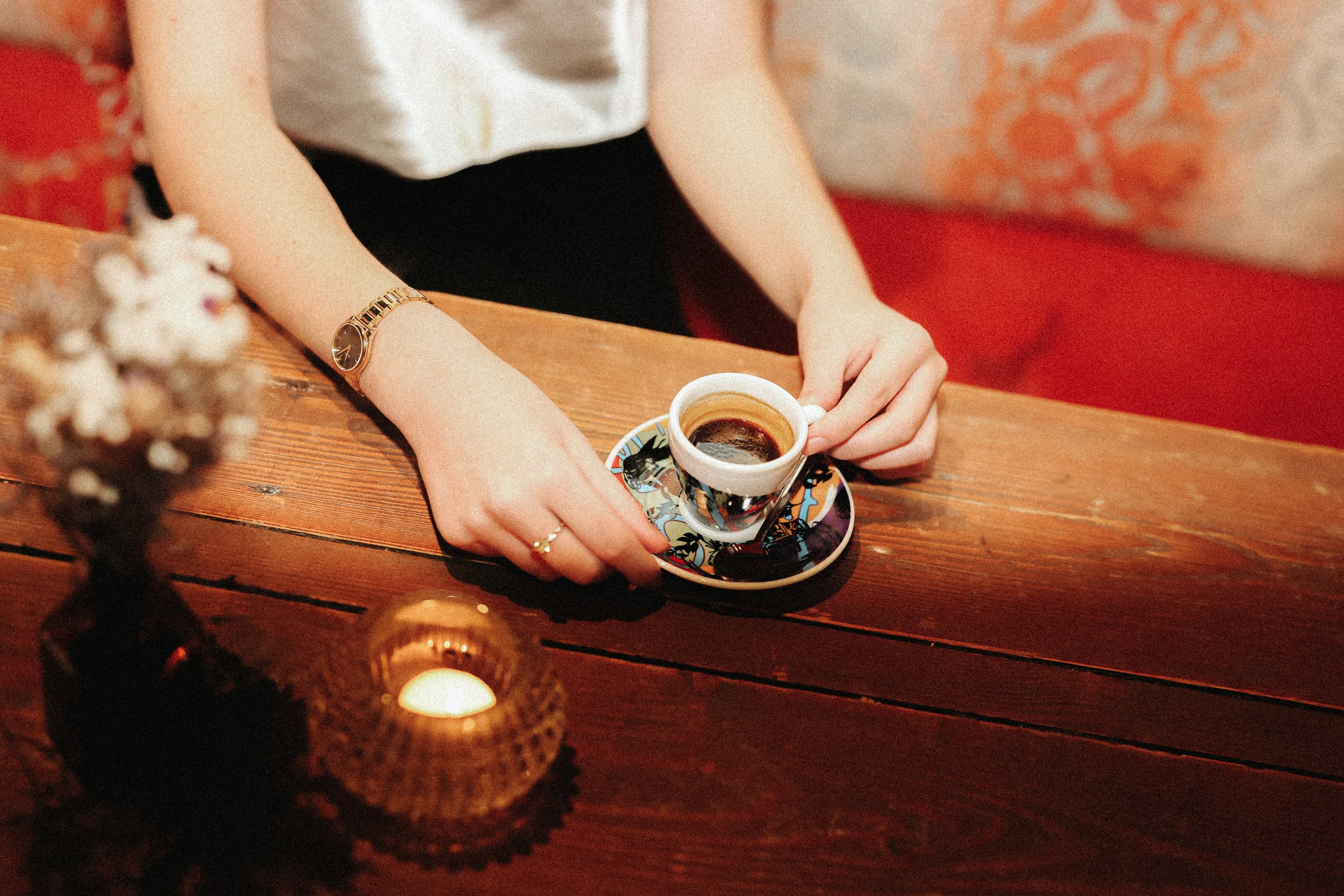 Une personne tenant une tasse de café sur une table en bois.