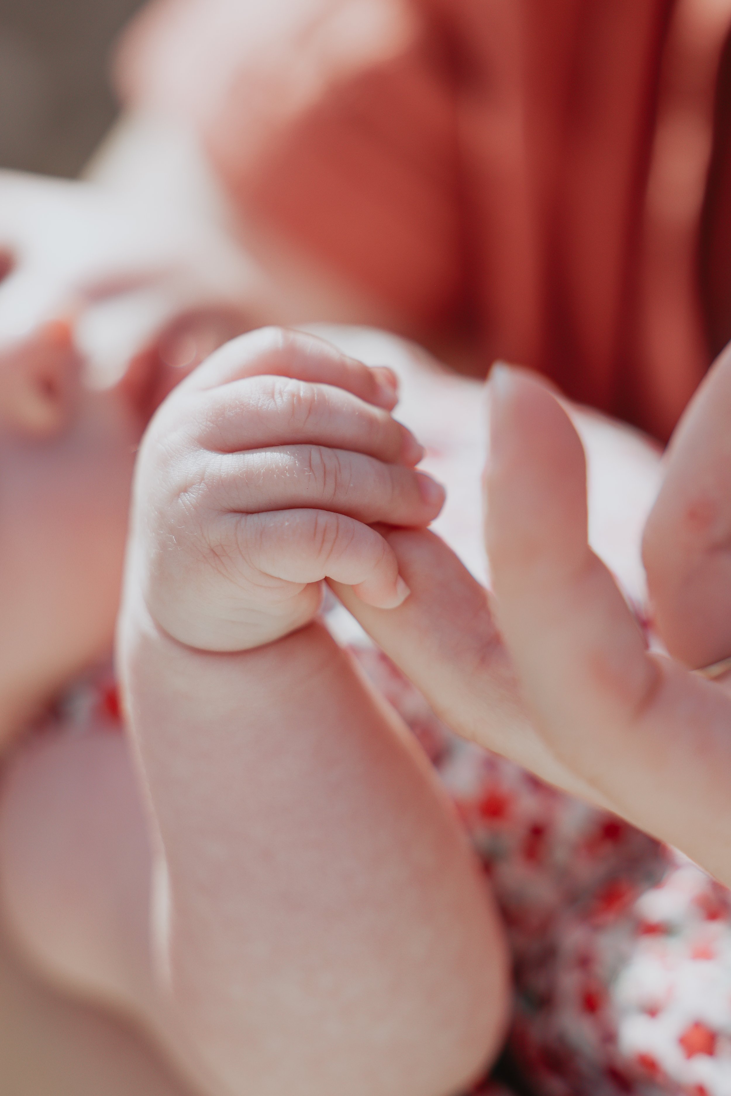 Gros plan d'un bébé tenant la main d'un adulte, avec des vêtements à motifs étoiles. La scène dégage une impression d'affection et de tendresse.