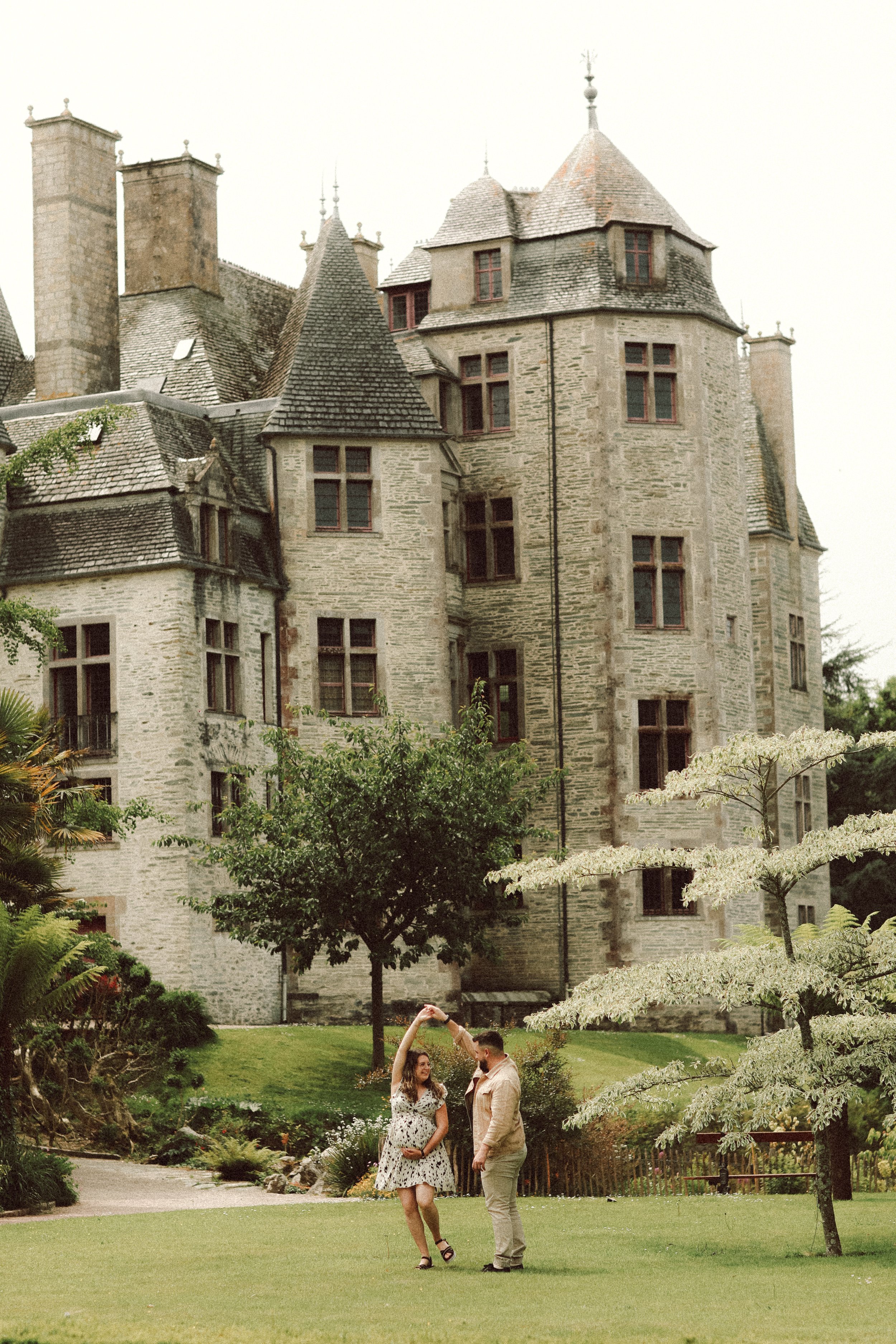 Un couple dansant dans un jardin devant un vieux château en pierre