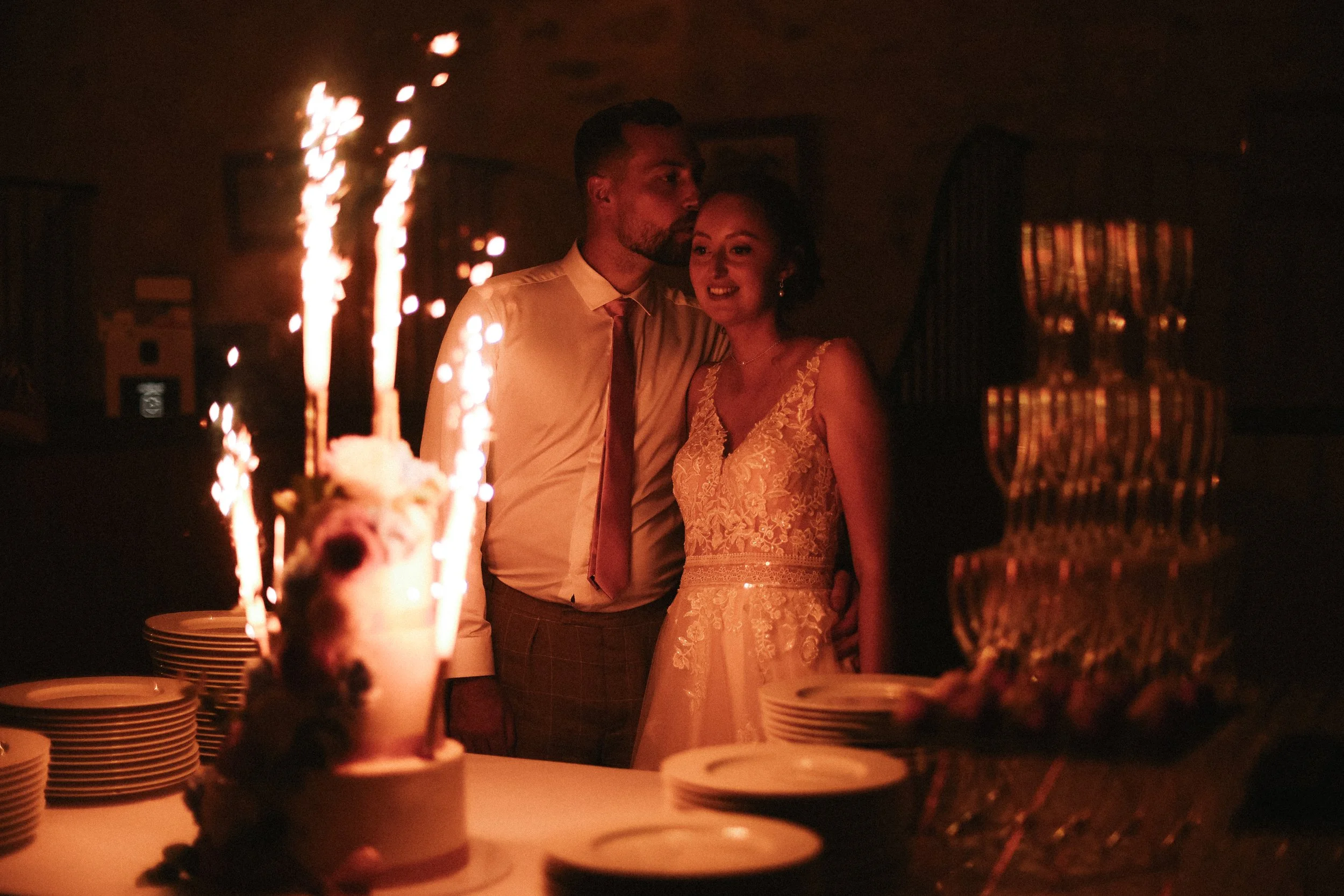 Un couple lors d'une fête, entouré de gâteaux et de feux d'artifice, dans une ambiance chaleureuse et intime.
