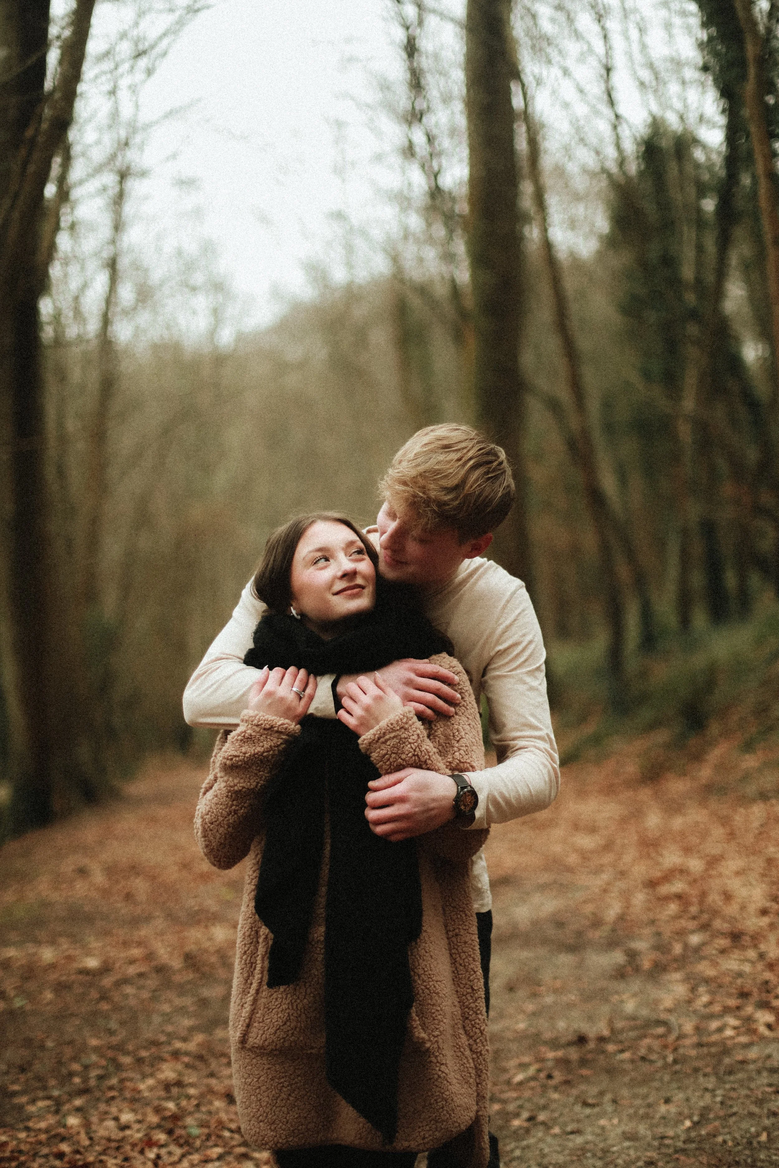 Un couple s'embrasse dans une forêt en automne.