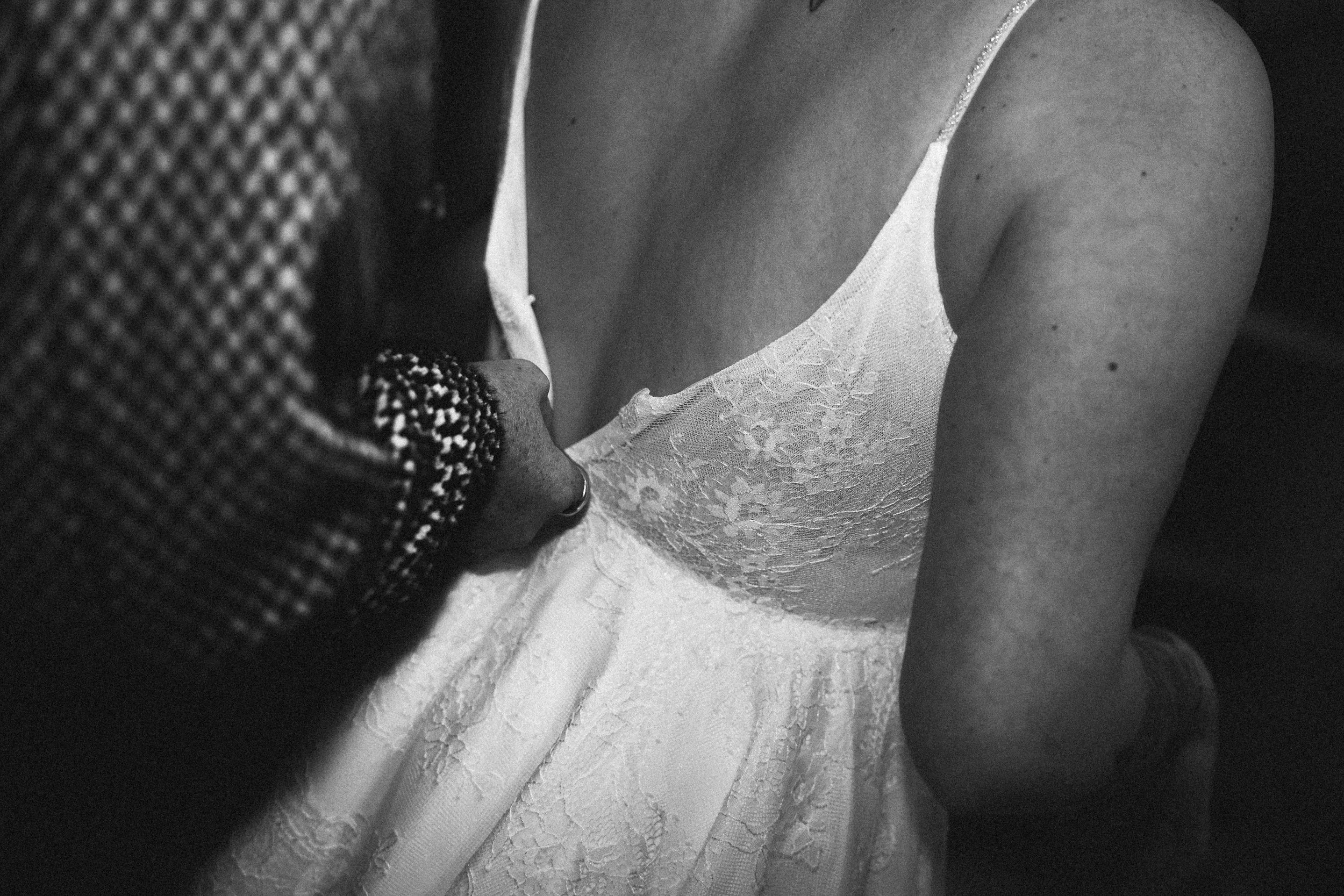 Une femme en robe de mariée en dentelle blanche, montrée en plan rapproché en noir et blanc.