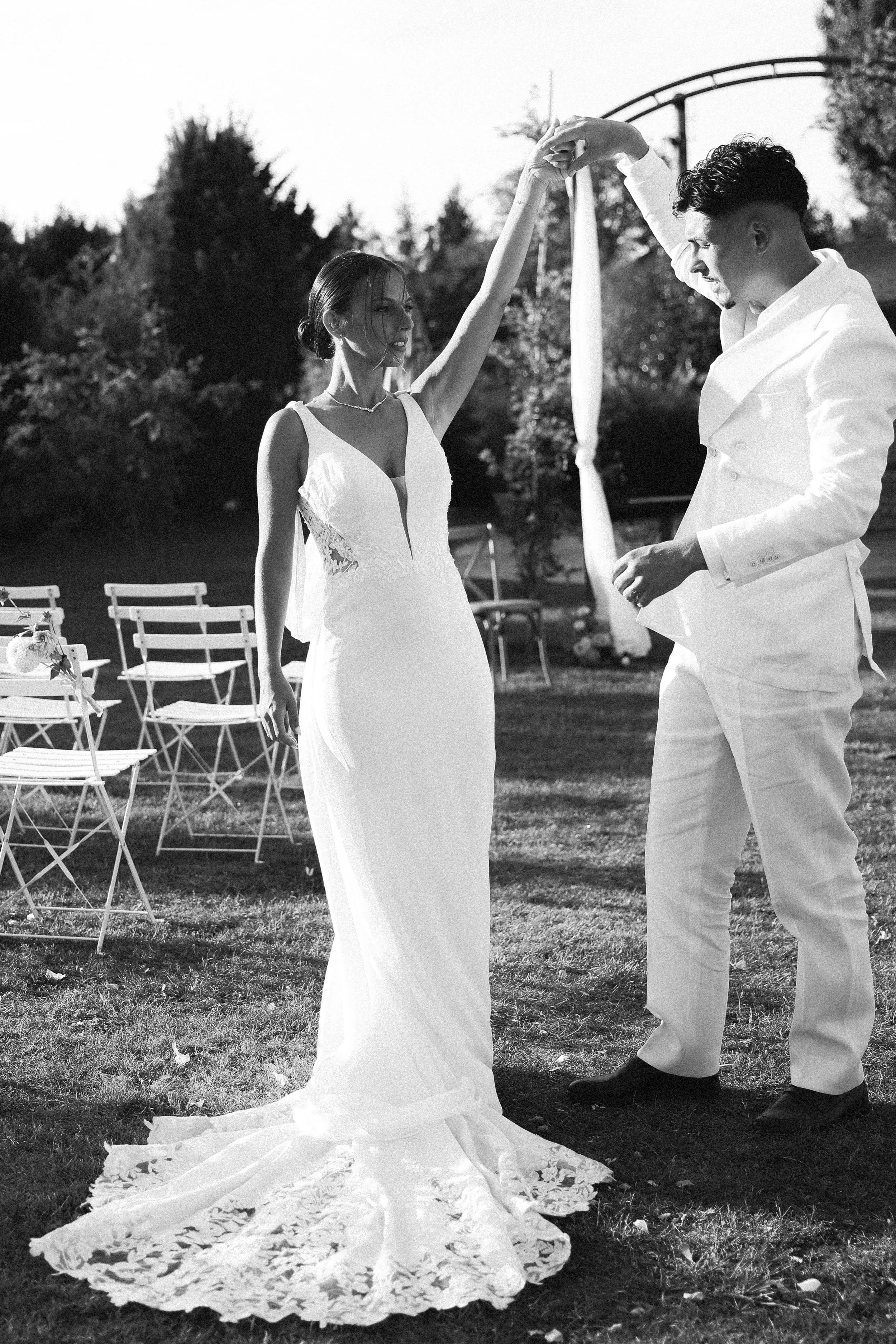 Couple en robe de mariée et costume blanc échangeant un danse lors d'un mariage en plein air.