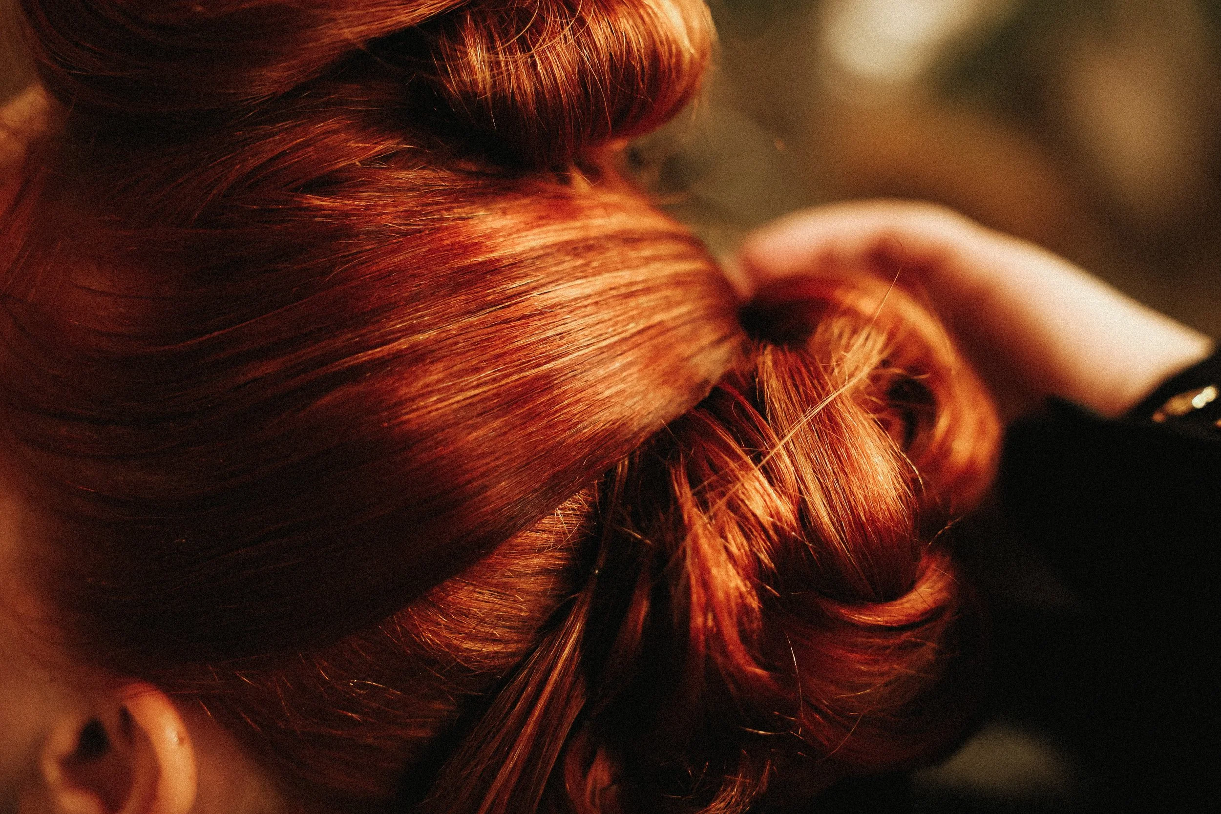 Cheveux roux brillants et bouclés d'une femme, capot appris, tenant ses cheveux.