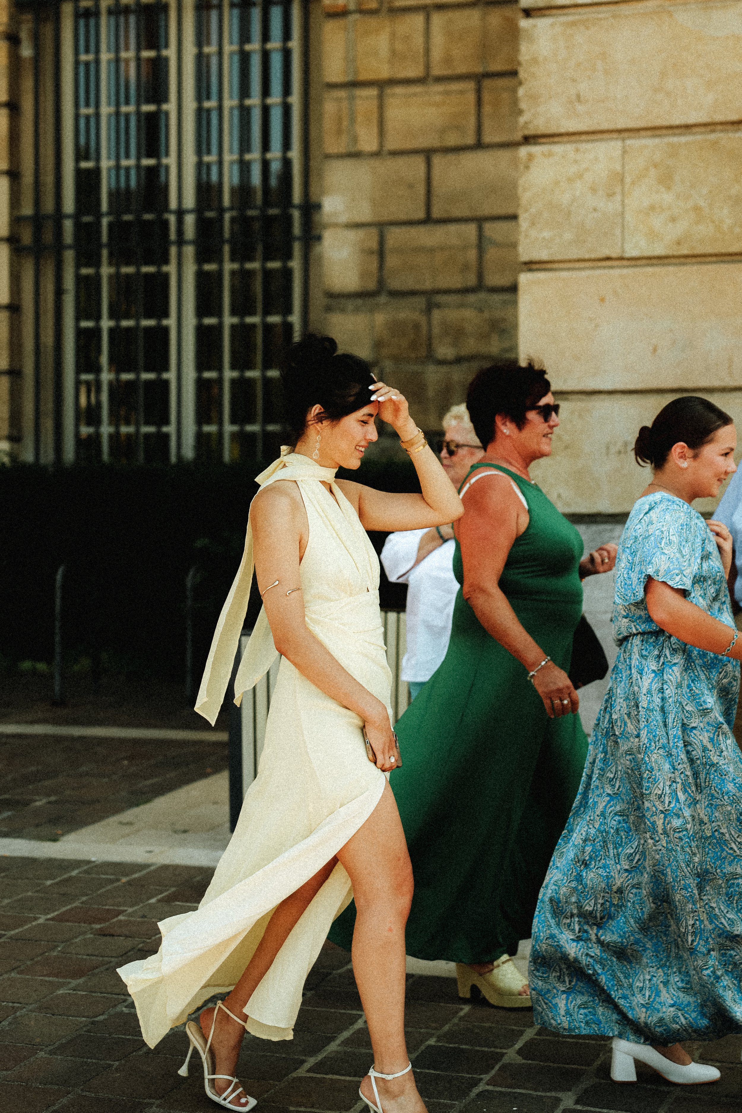 Groupe de femmes élégantes marchant dehors, vêtues de robes colorées.