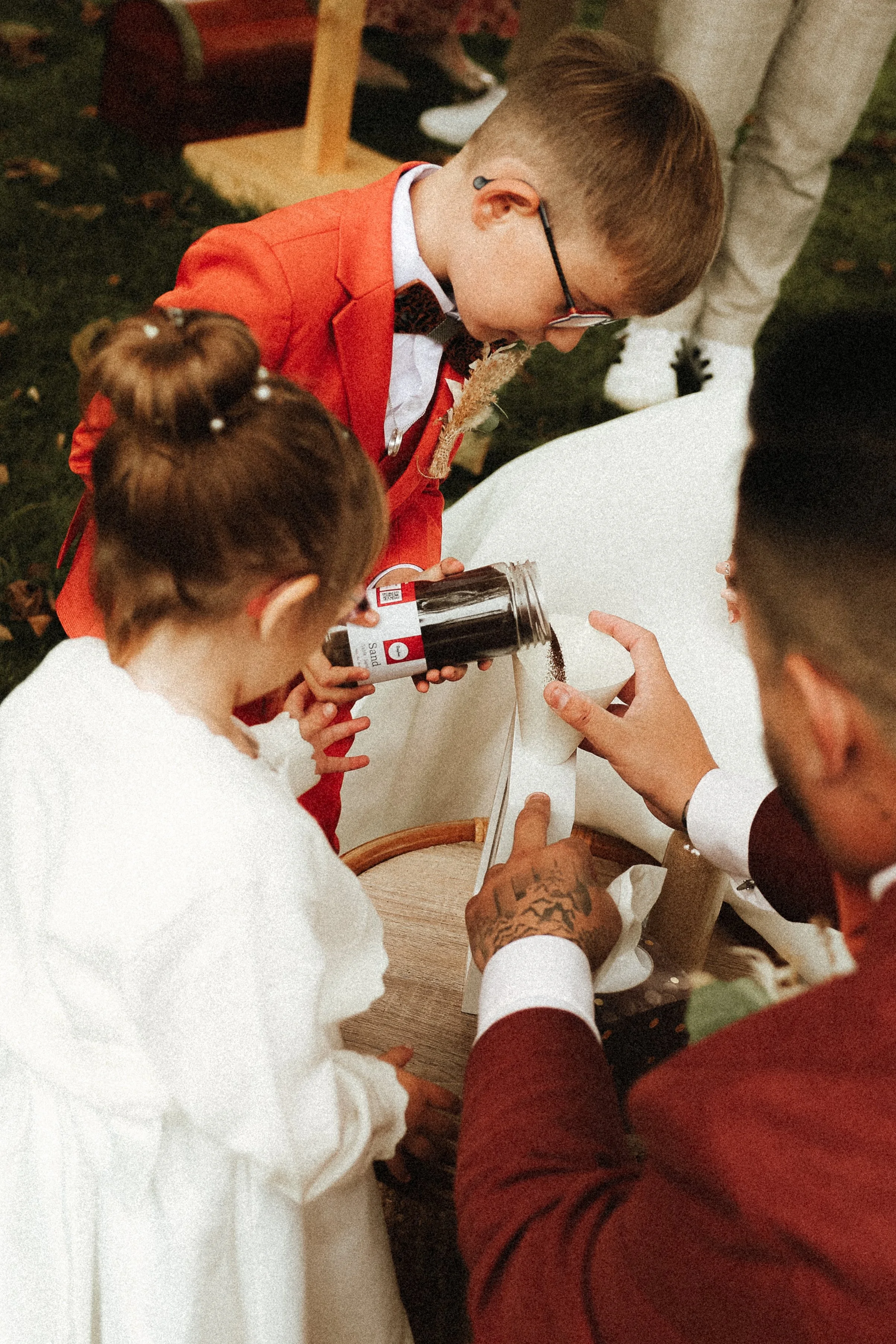 Groupe de personnes participant à une cérémonie ou un rituel, versant un liquide sombre sur un objet blanc, lors d'une célébration en extérieur.