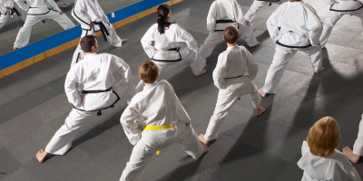 Martial arts students practicing in white uniforms on a dojo mat.