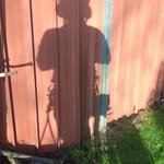 Shadow of a person standing near a wooden fence during sunset.
