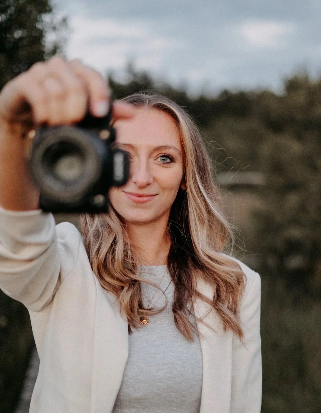 Eine Frau macht ein Selfie mit einer Kamera draußen im Freien.
