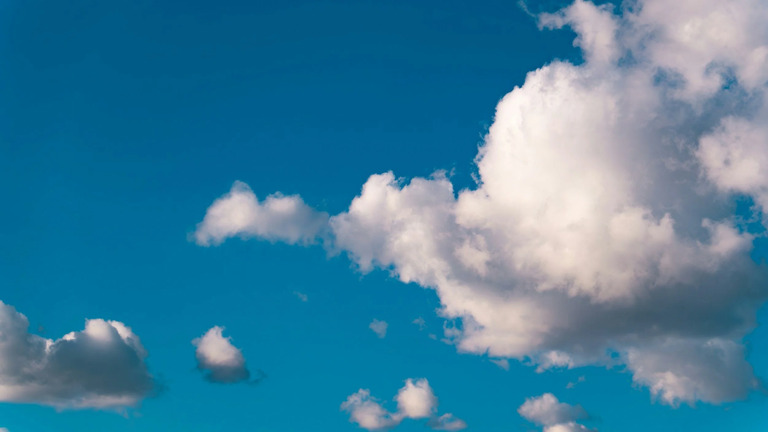 Blue sky with white, fluffy clouds scattered across.