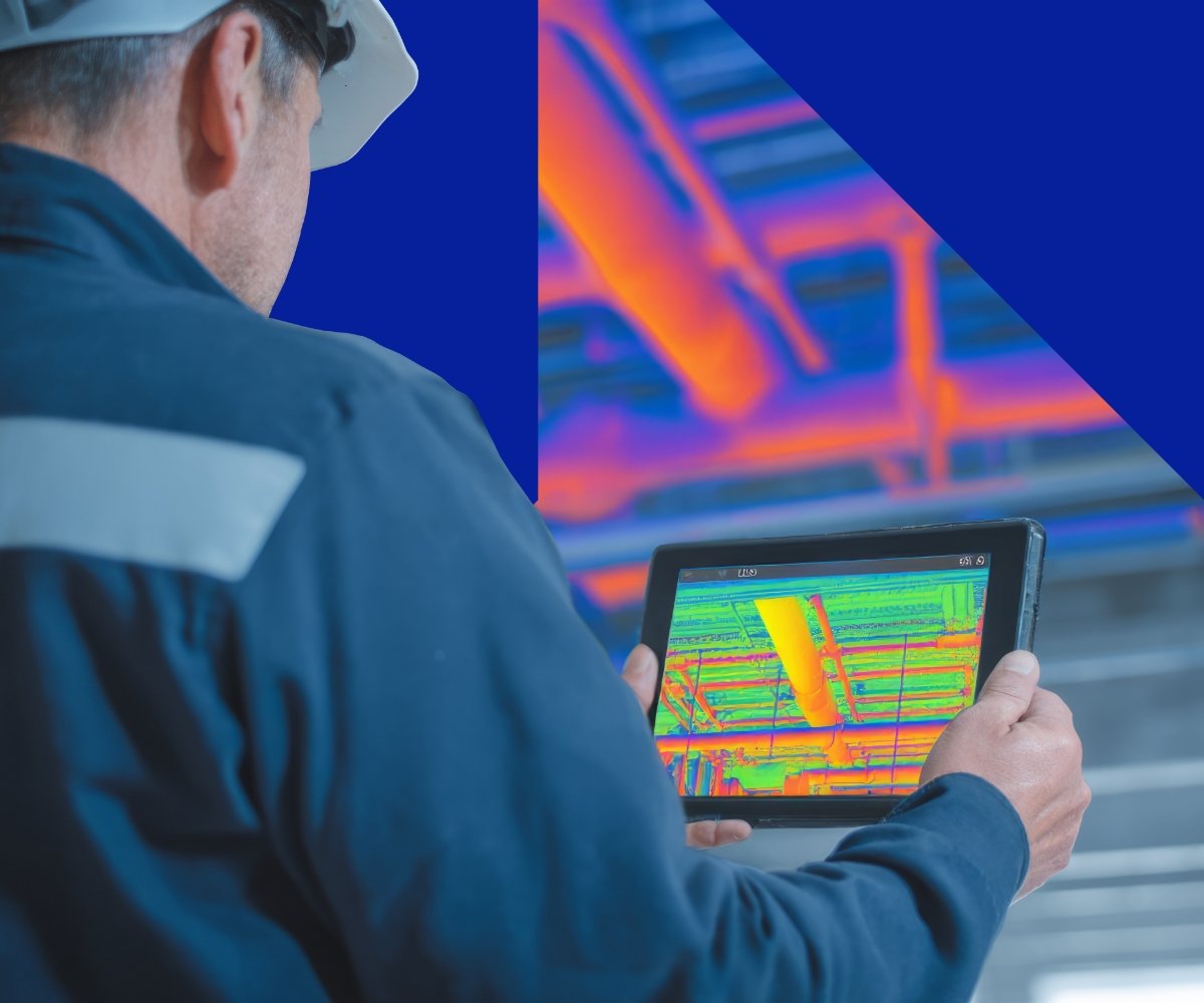 An engineer wearing a hard hat and protective clothing using a tablet with a colorful thermal or structural scan, with a background of a brightly lit industrial or warehouse shelving system.