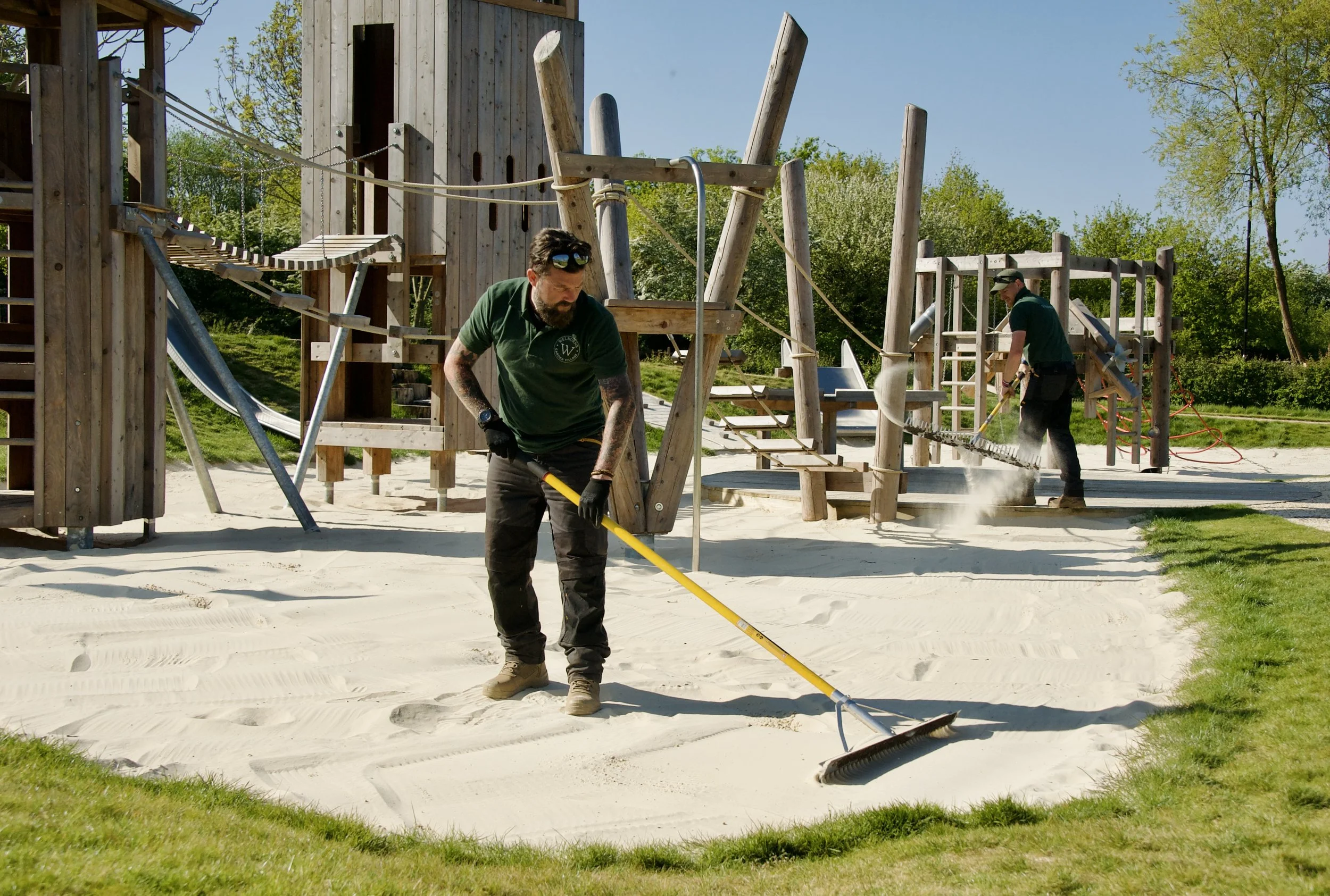 photo of groundsman raking sand in playpark