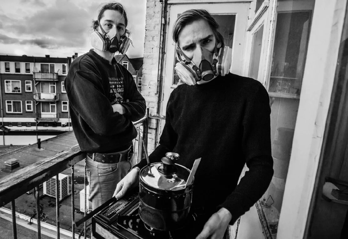 Archive: plasticiet founders Joost and Marten T wearing face masks and black sweaters on a balcony.