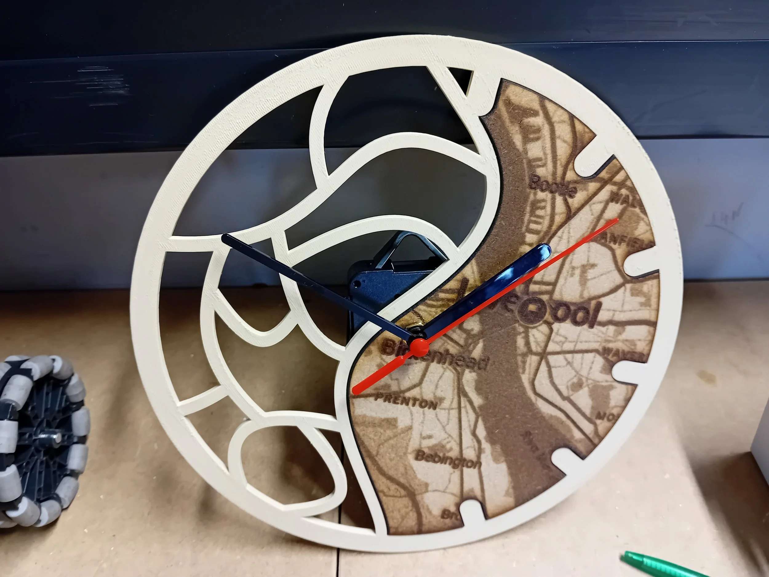 Decorative wall clock with a cutout design resembling a city map, featuring black hour and minute hands, a red second hand, and a map of Boston with labeled neighborhoods.