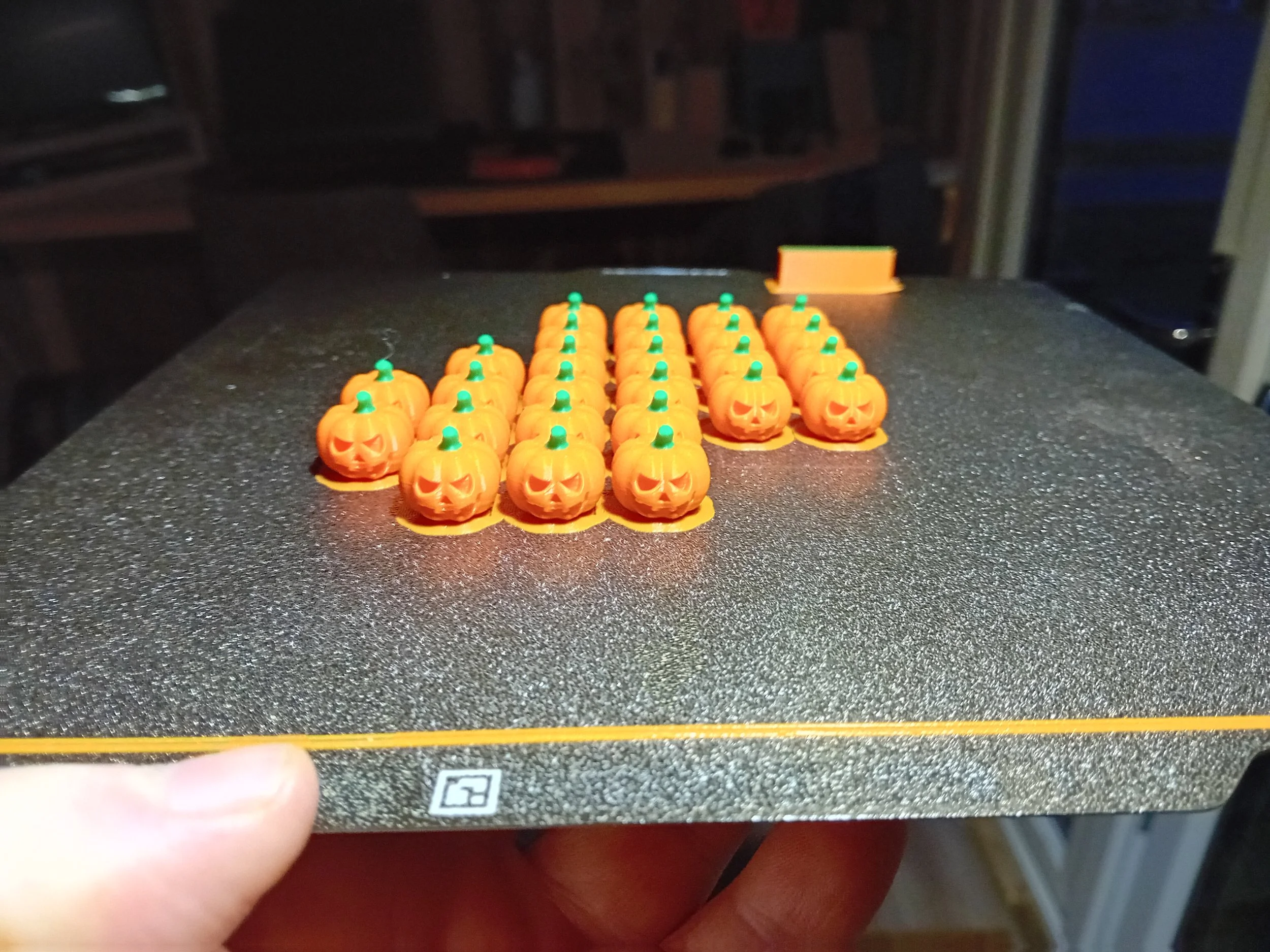 Small plastic Halloween pumpkins with carved faces, arranged in rows on a table.