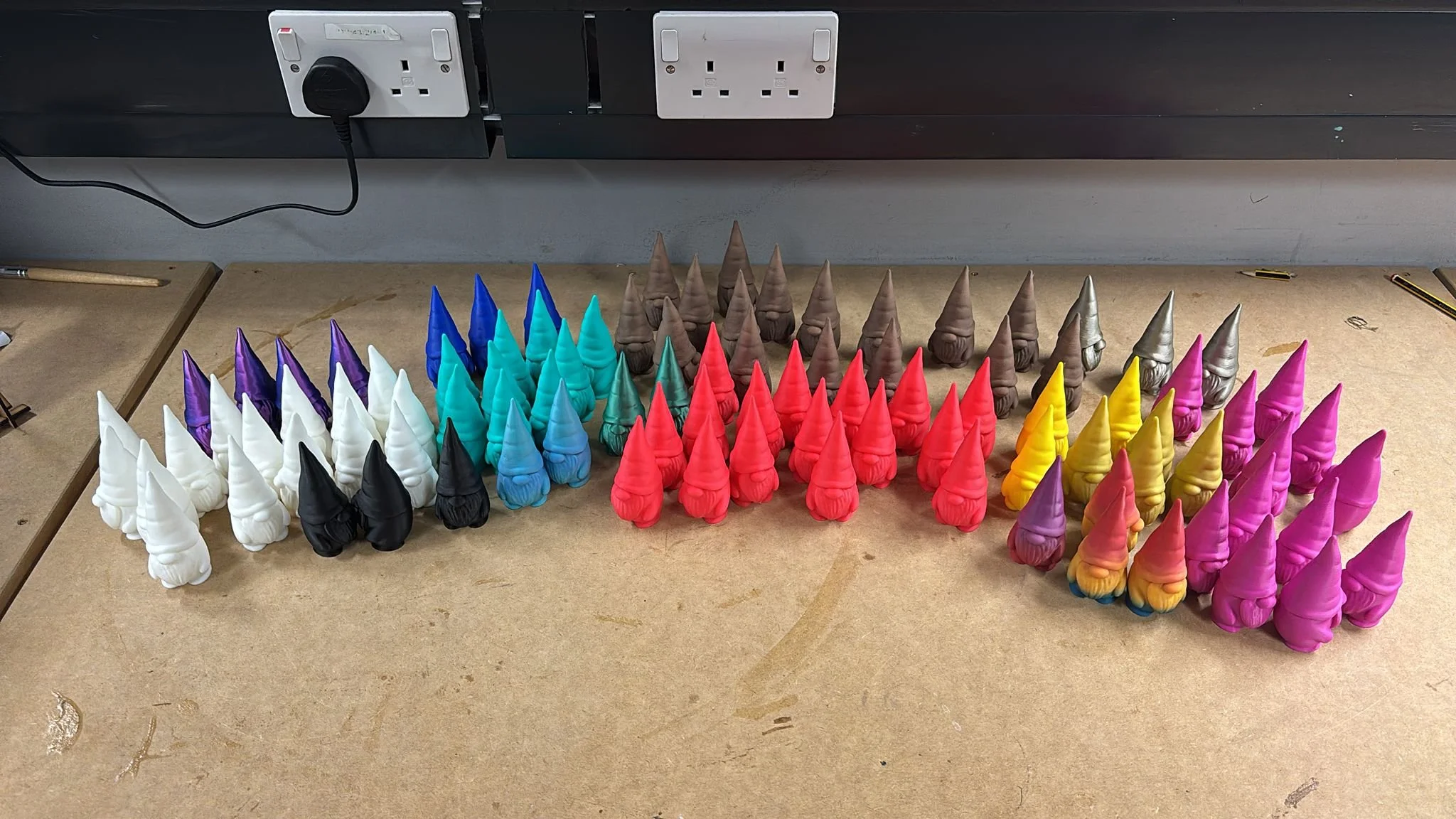 Colorful gnome figurines arranged in a semi-circle on a workbench.