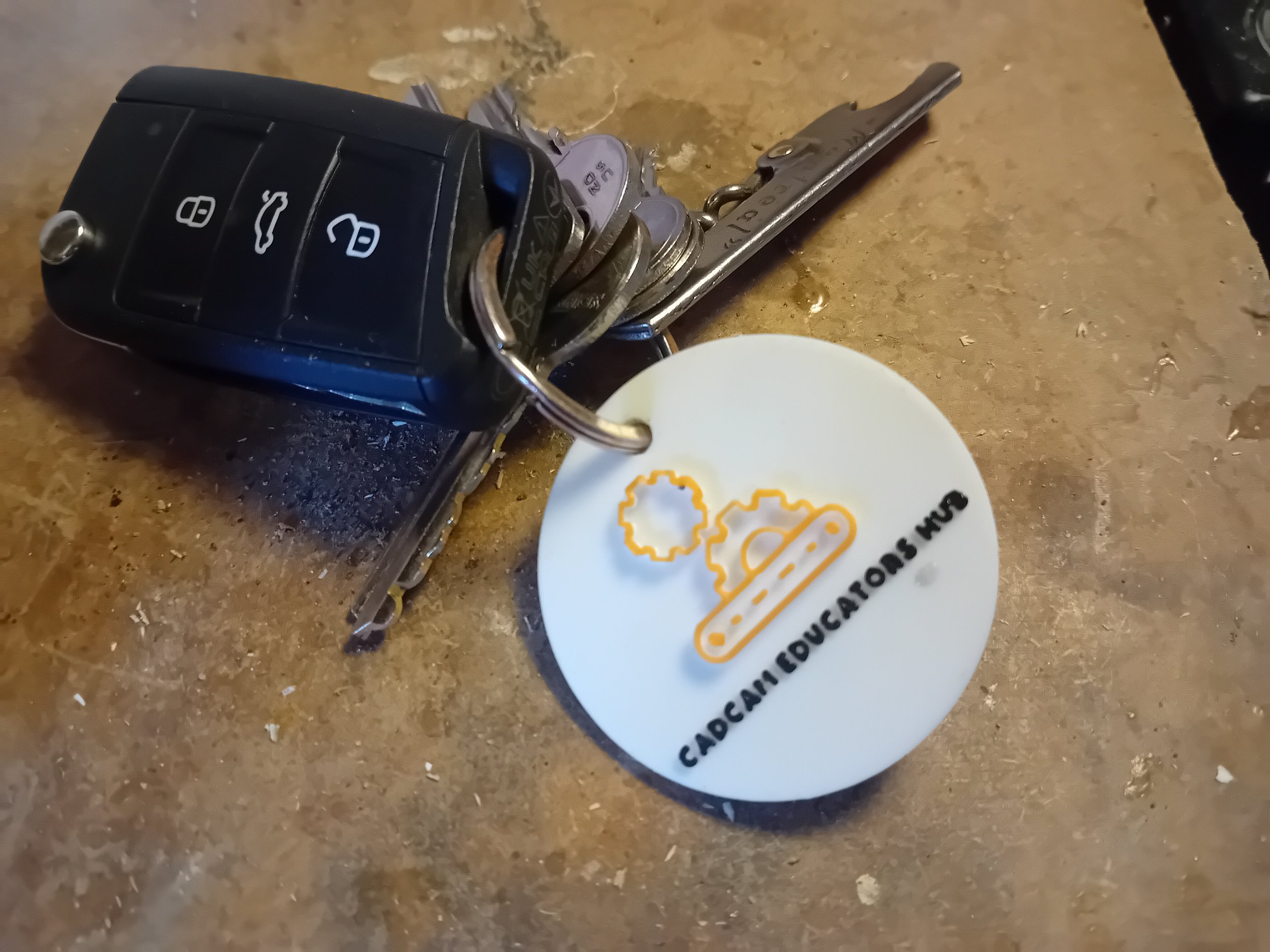 Car key with a white circular tag attached, resting on a brown surface.