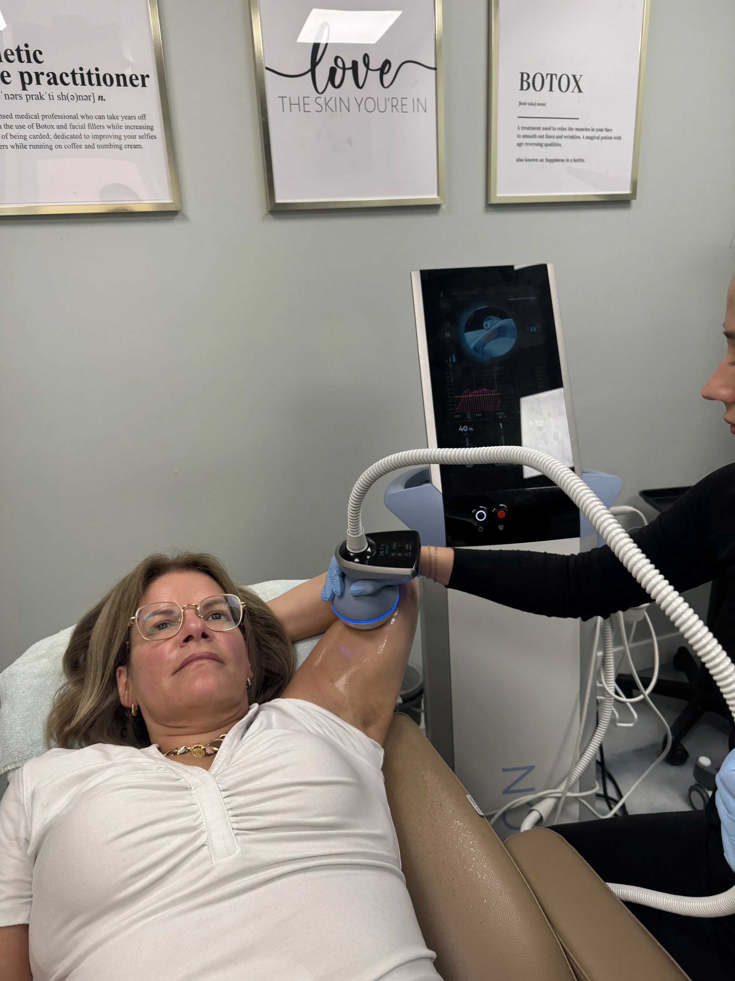 A woman receiving a medical procedure involving a device emitting blue light while lying on a chair at a clinic.