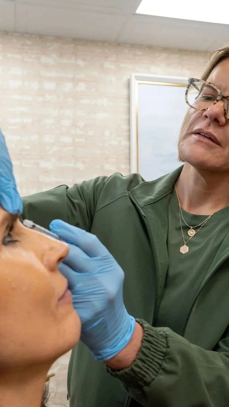 A healthcare professional wearing blue gloves examining a woman's eye in a clinical setting.