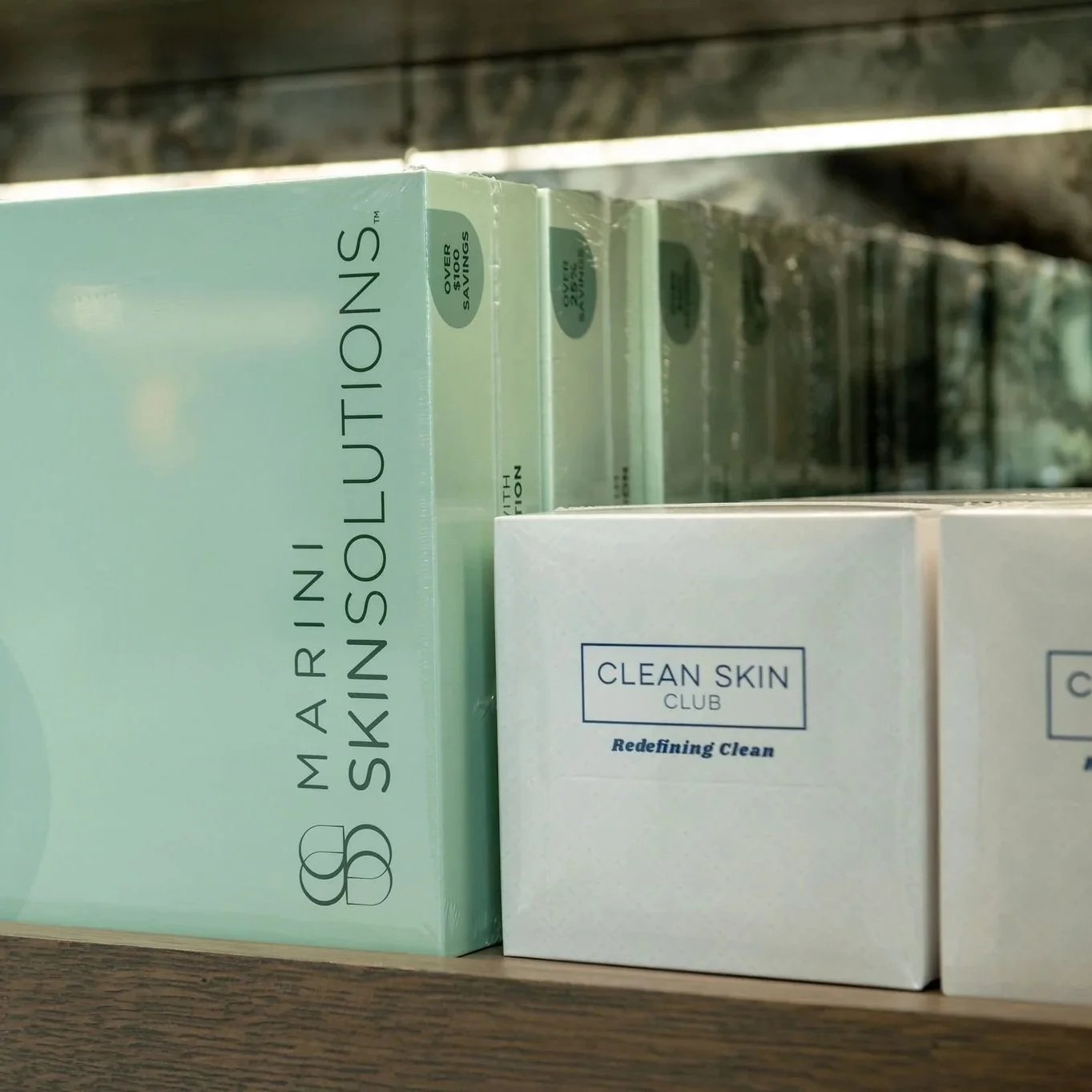 Boxes of skincare products on a shelf, including a Mariniu Solutions skincare box and a Clean Skin Club box in white packaging.