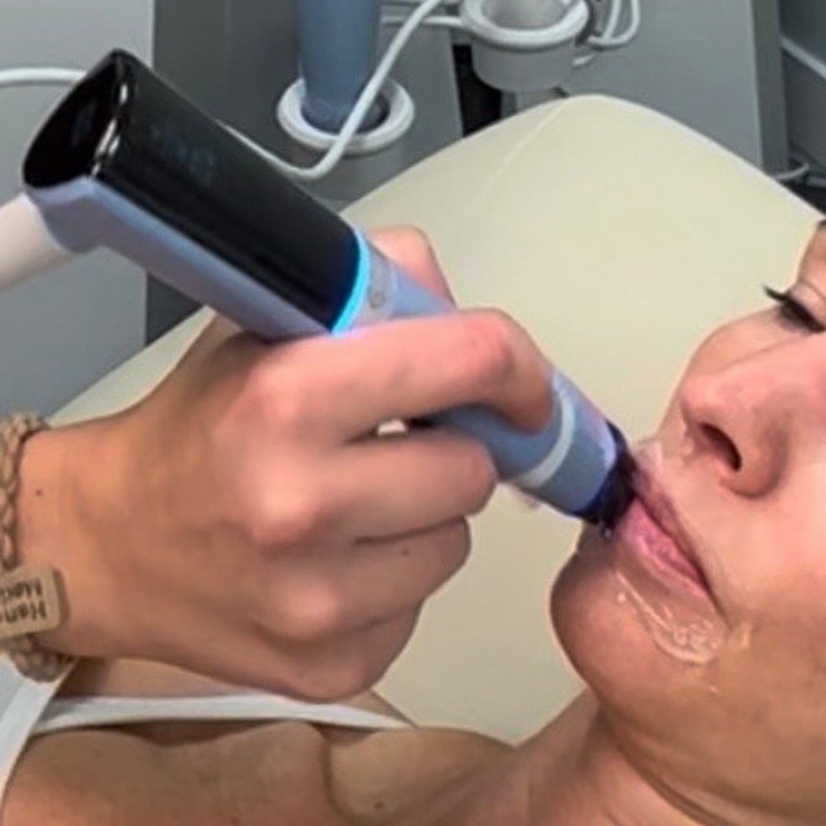A woman receiving a medical examination using a handheld device in a clinical setting.