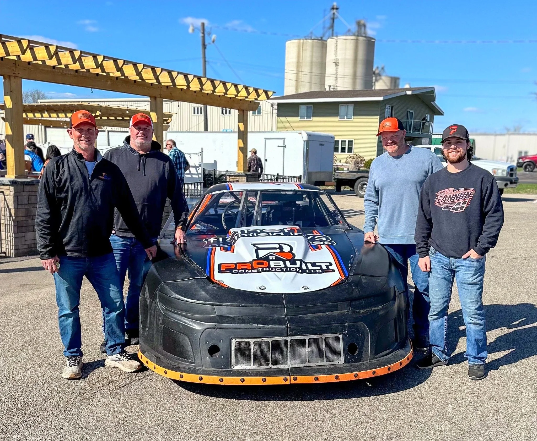 ProBuilt founders standing near a sponsored race car.