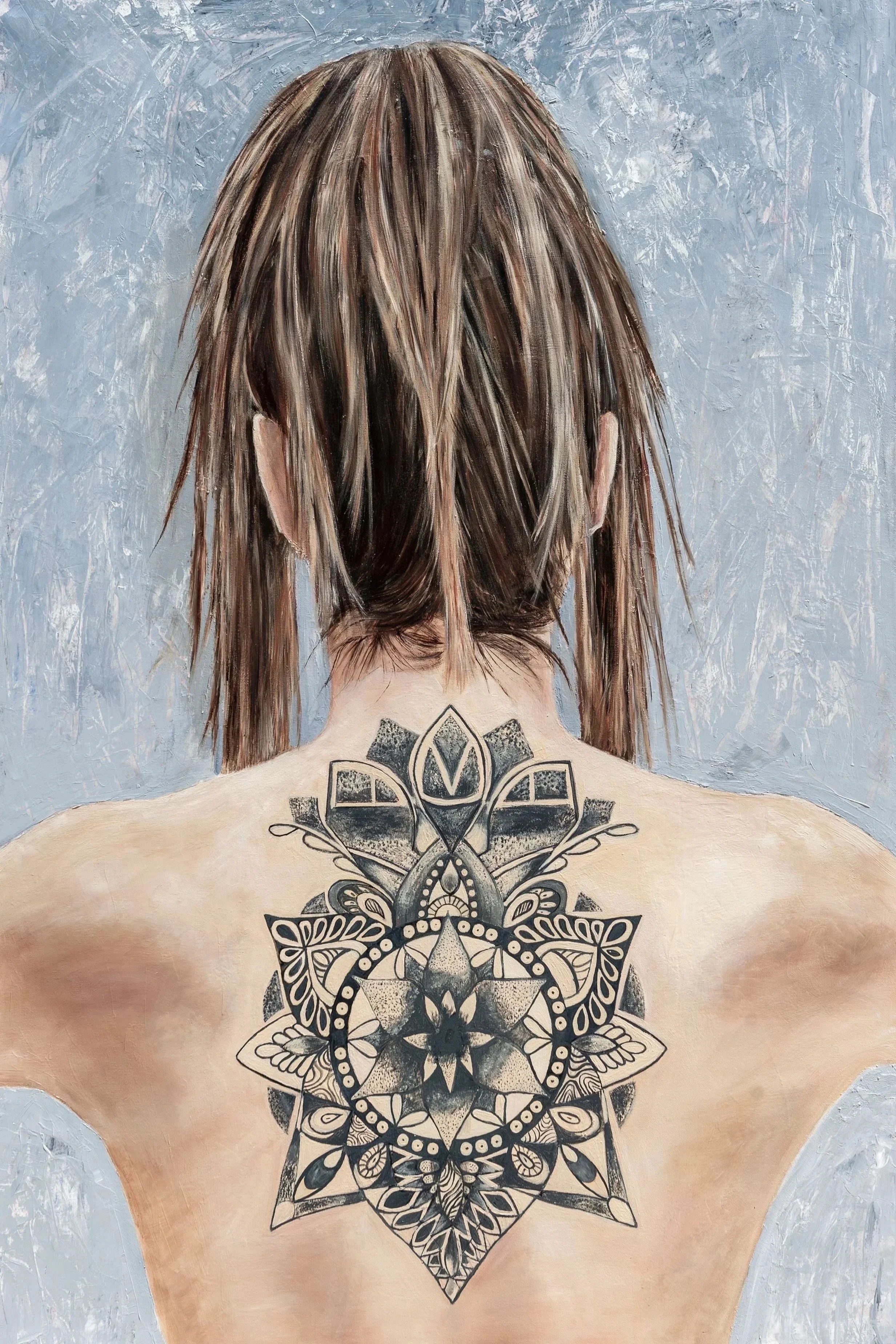 Back of a woman with a shoulder tattoo of a large black and white mandala design.