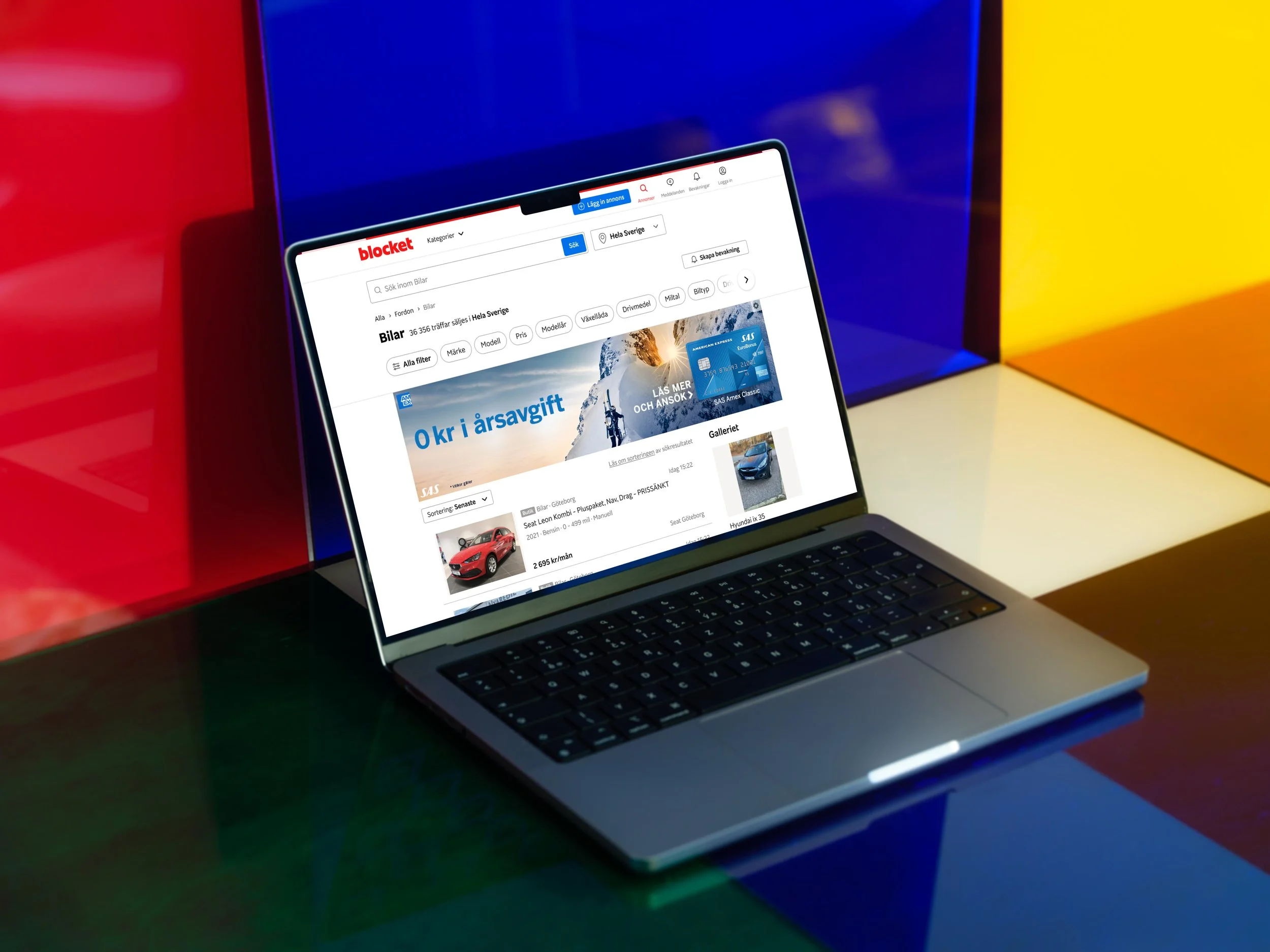 A laptop on a colorful table with a website for buying cars open on the screen.