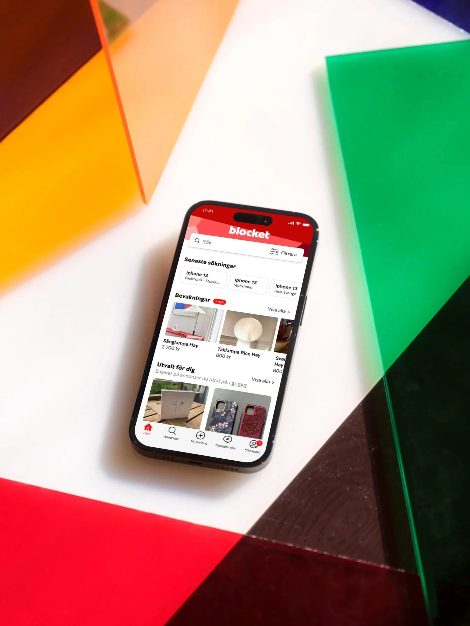 An iPhone displaying the Blocket app resting on a multicolored surface with panels of red, yellow, green, and dark brown.