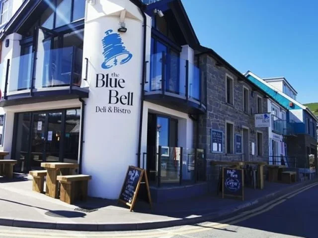 Exterior of a restaurant named The Blue Bell Deli & Bistro with outdoor seating and chalkboard signs