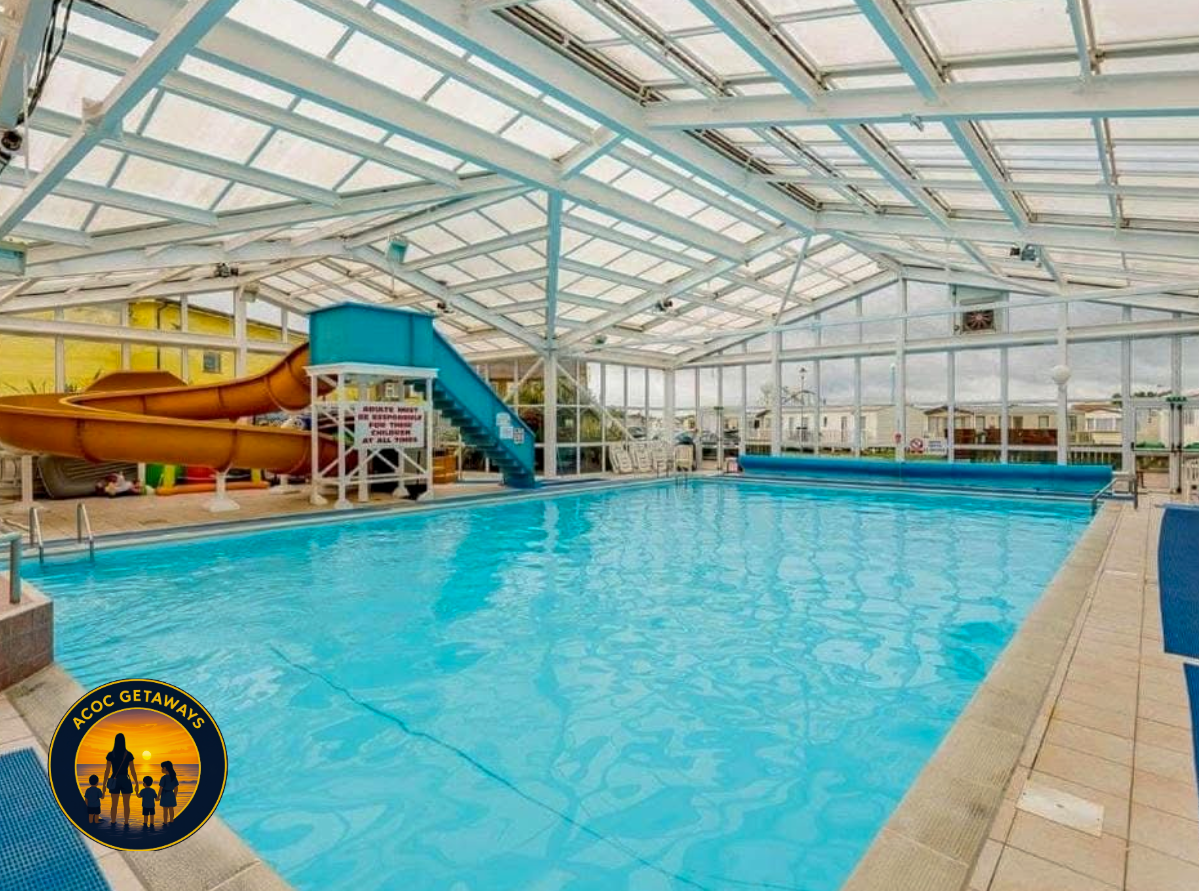 Indoor swimming pool with a water slide and a glass ceiling.